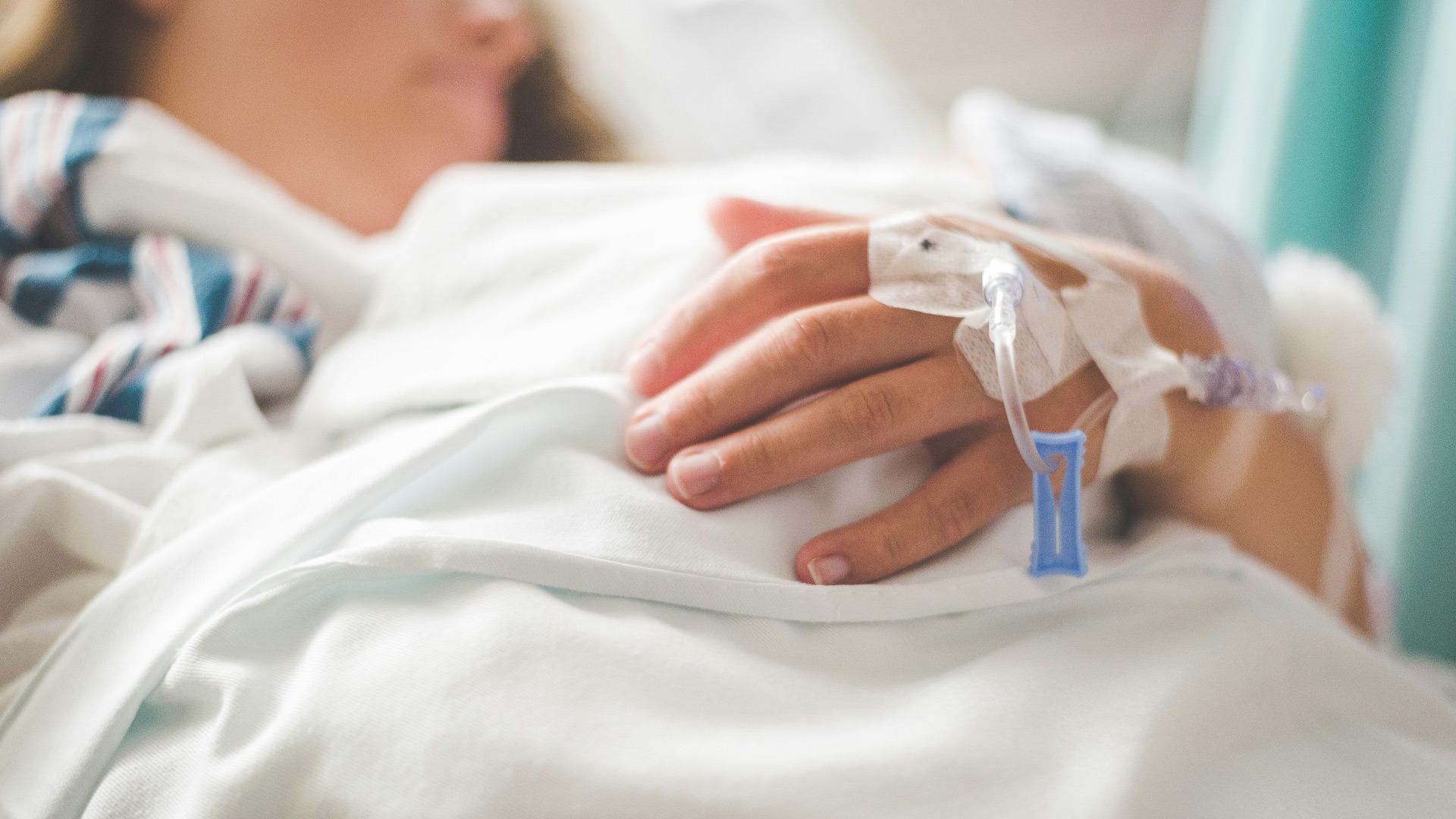 a woman laying in a hospital bed with an iv in her hand