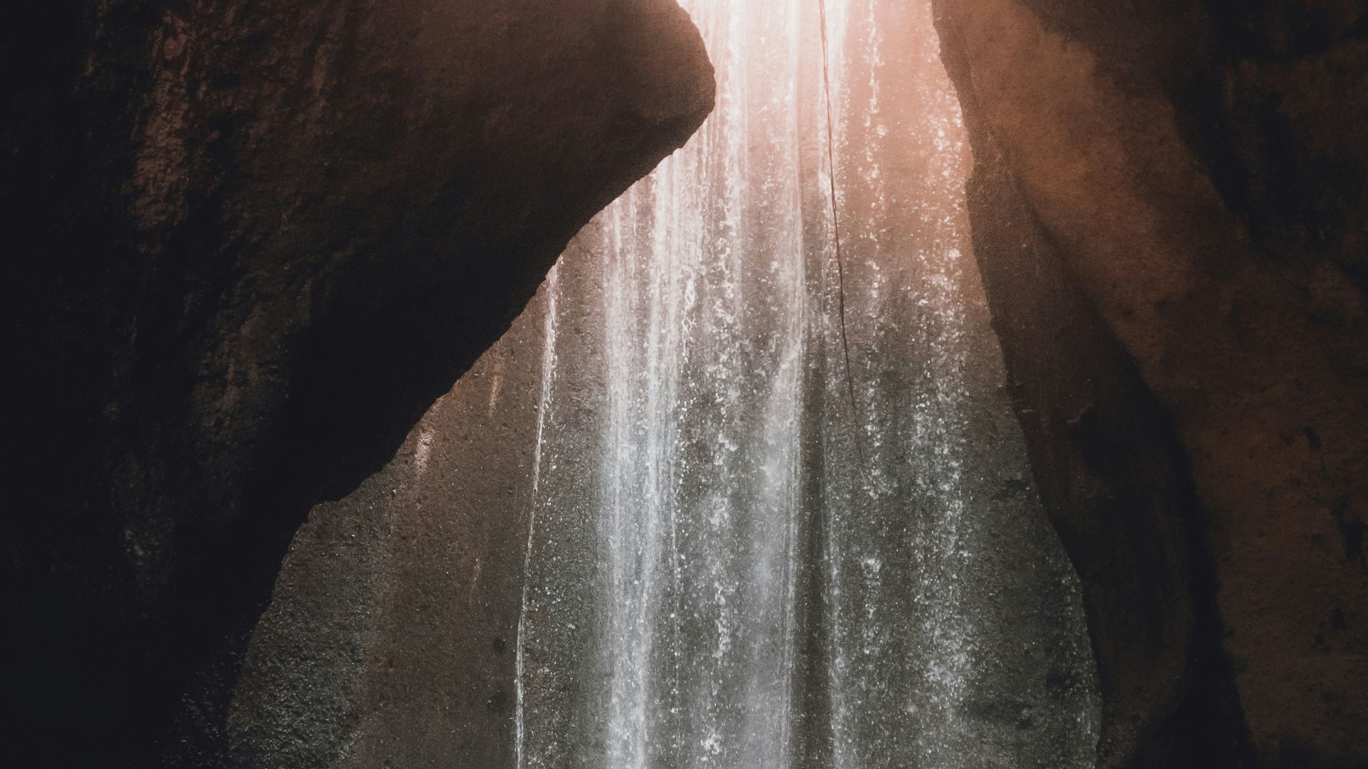 person standing on rock near waterfalls during daytime