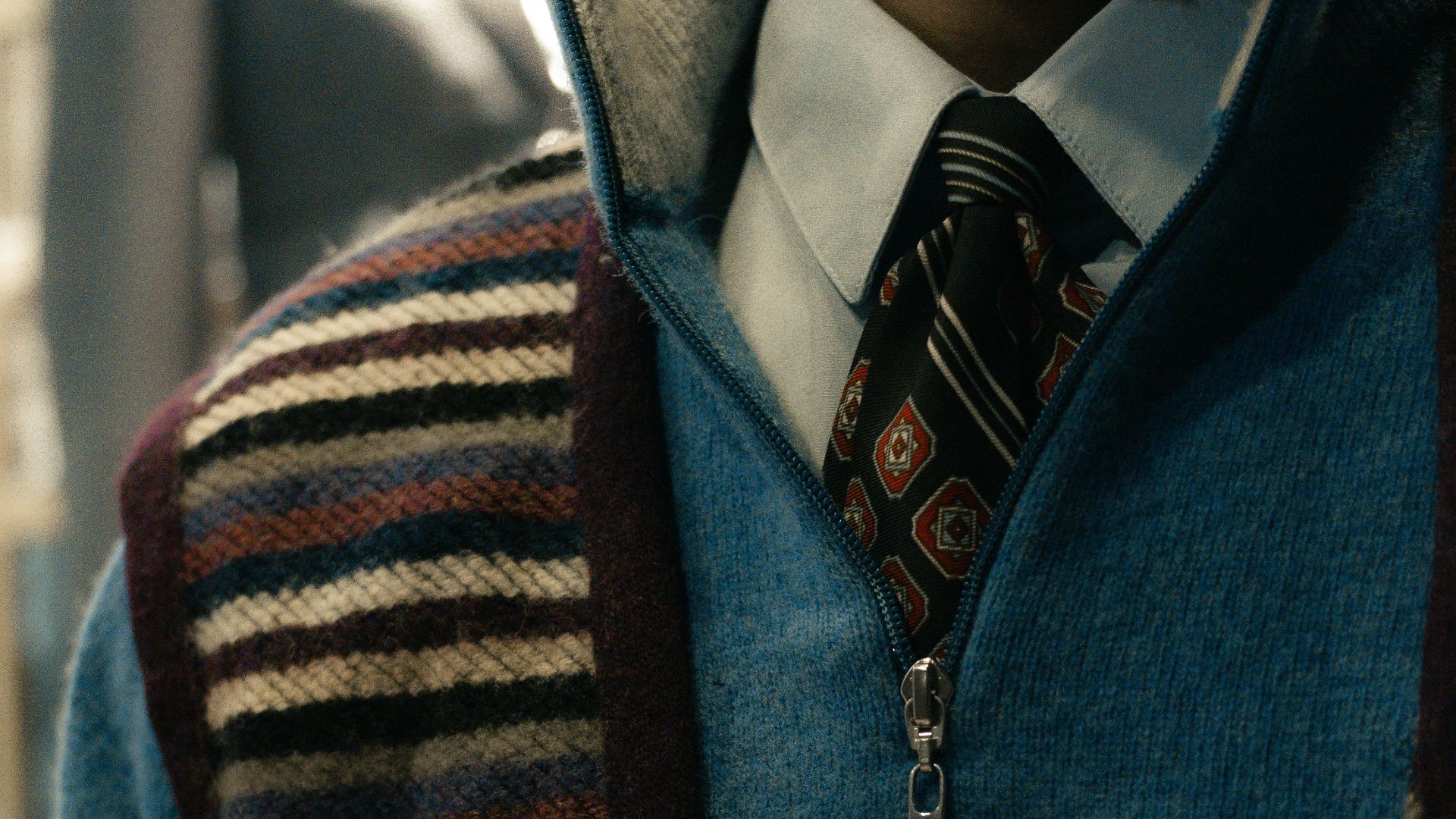 Man wearing a blue quarter-zip sweater over a collared shirt.