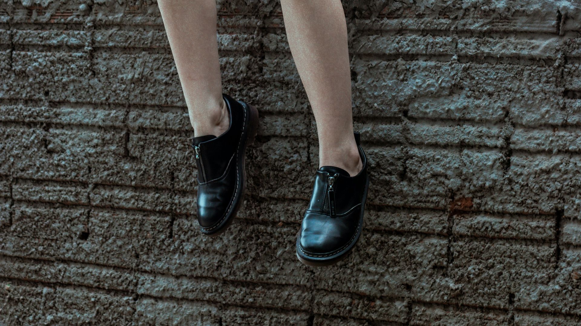 Woman in black outfit sitting on a ledge