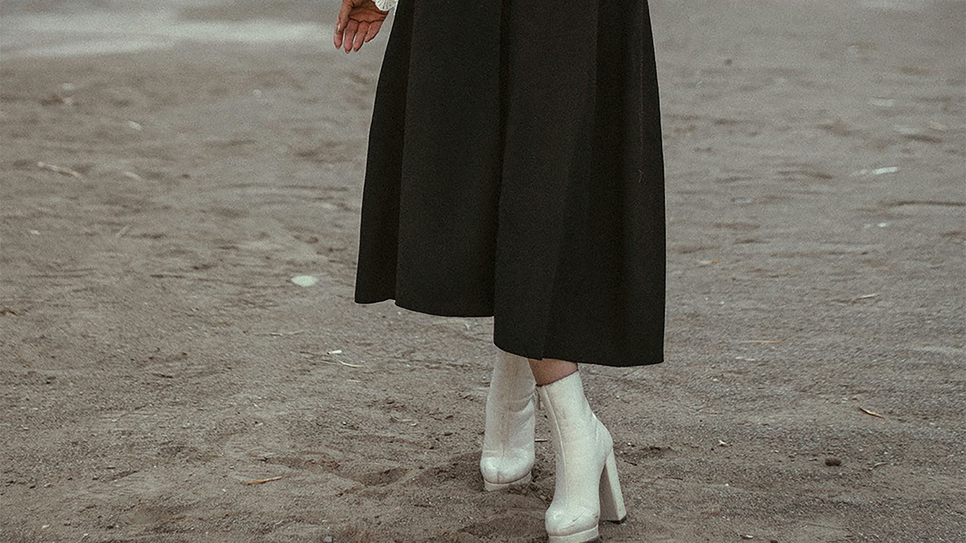 a woman wearing a black dress and white boots