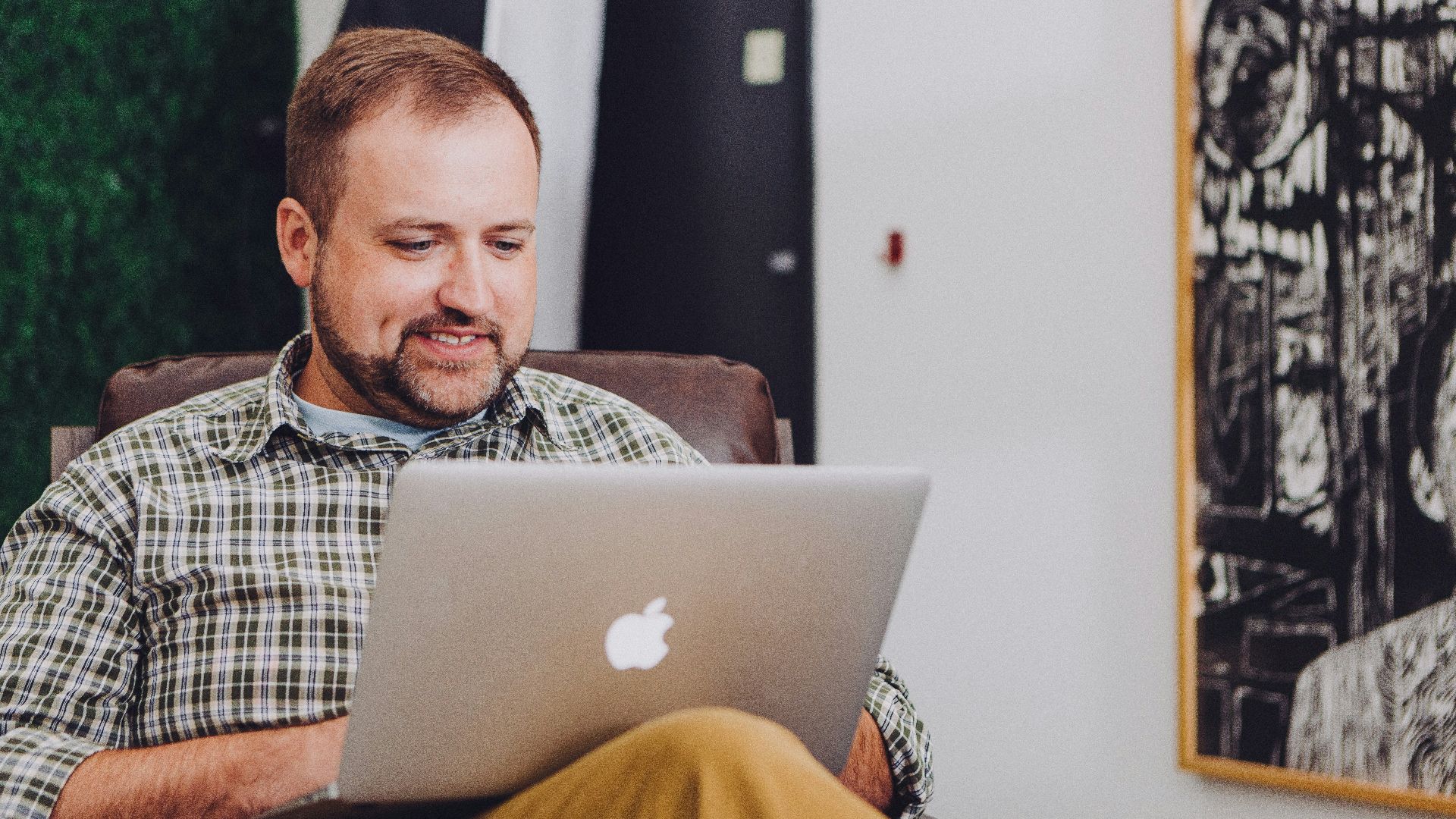 man smiling and using MacBook