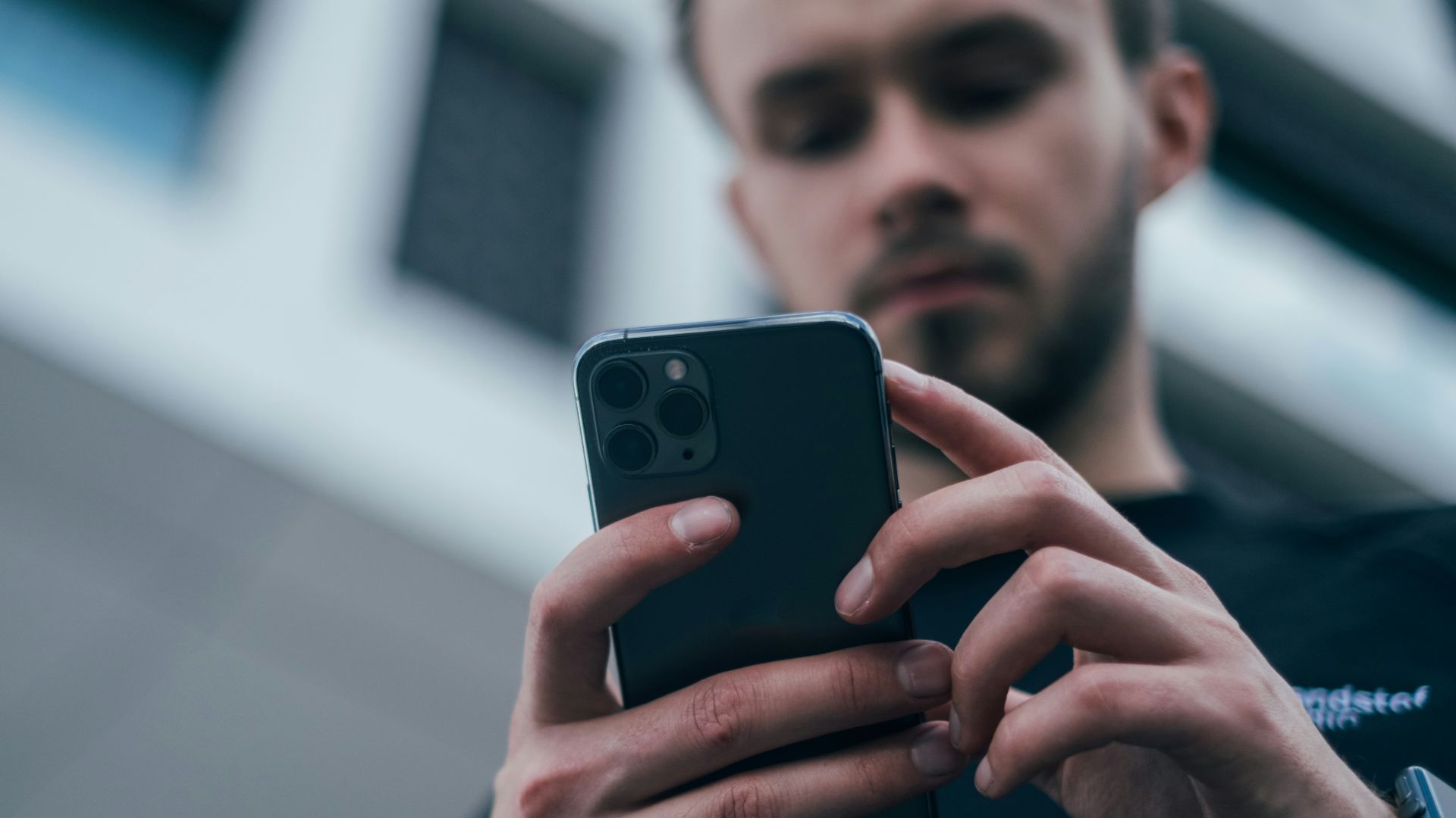 man wearing black sweater using smartphone