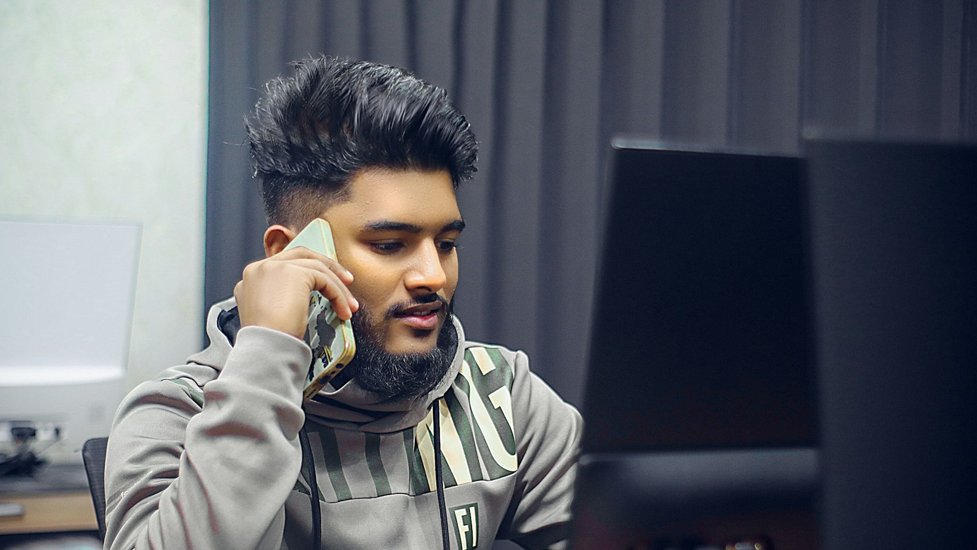 Man is on the phone in front of computer.