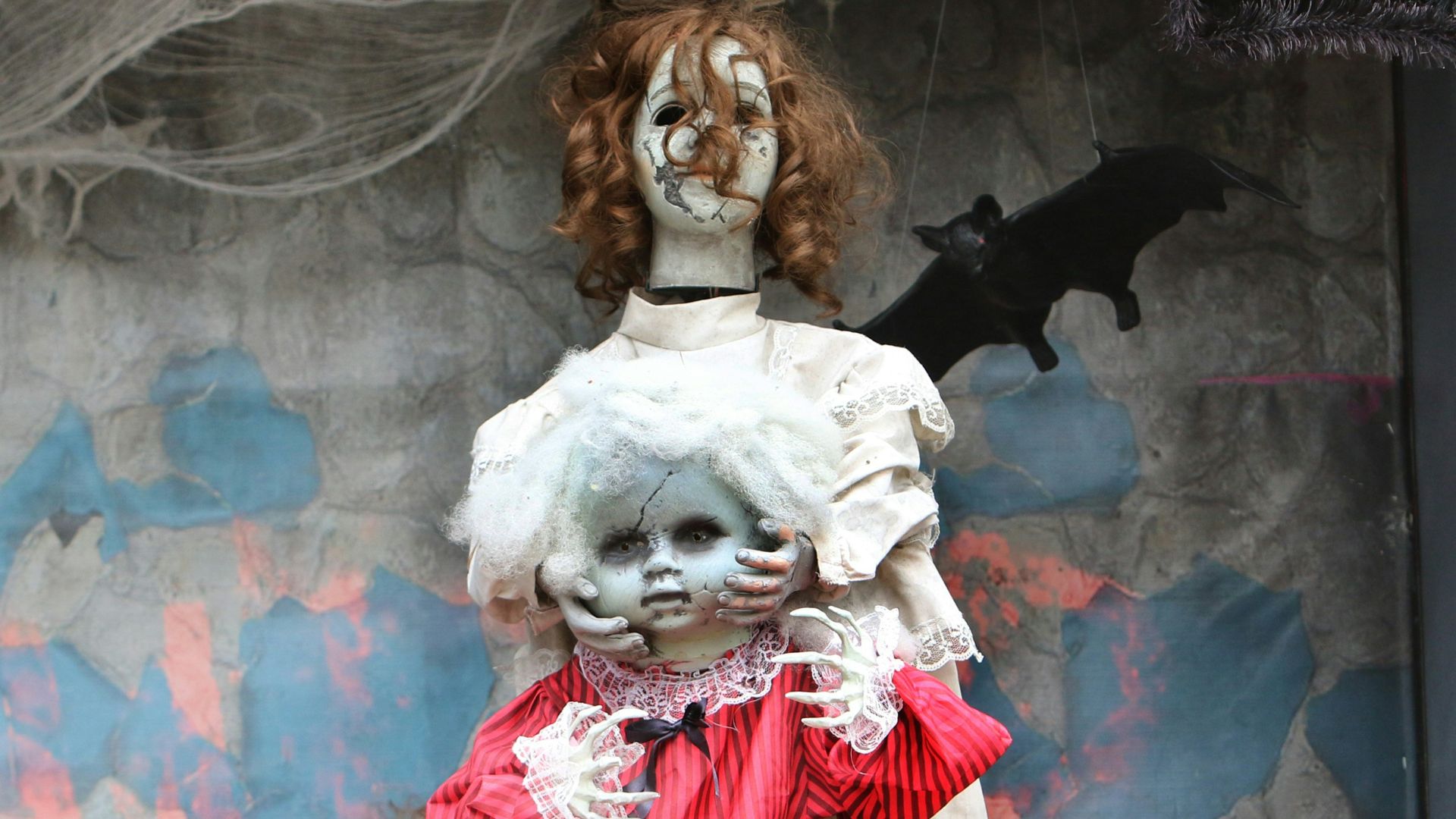 Two creepy dolls with tattered clothing and cobwebs