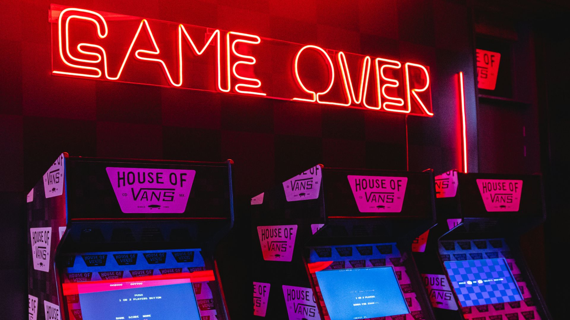 a neon sign that says game over in front of a row of arcade machines