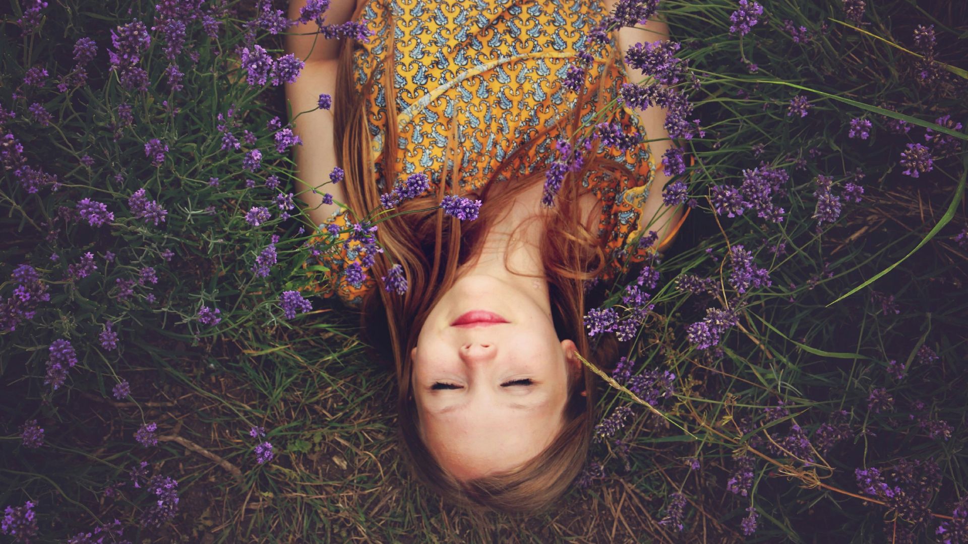 woman in yellow and teal top sleeping beside lavenders