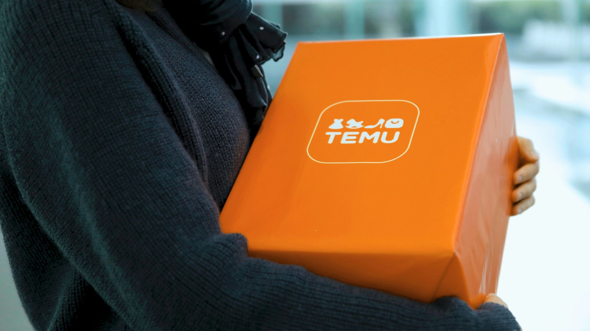 Woman holding an orange temu package