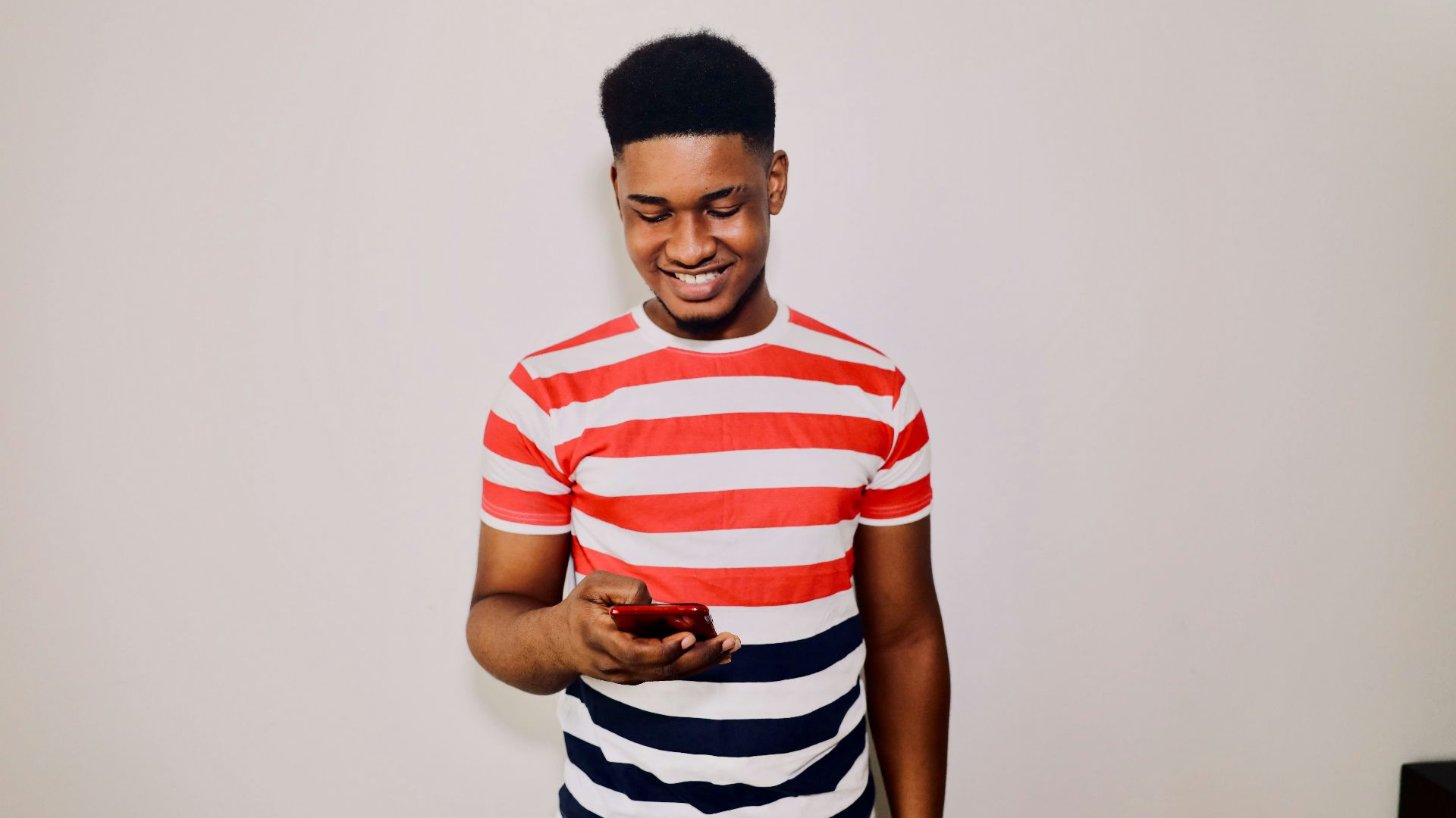 a man in striped shirt holding a cell phone