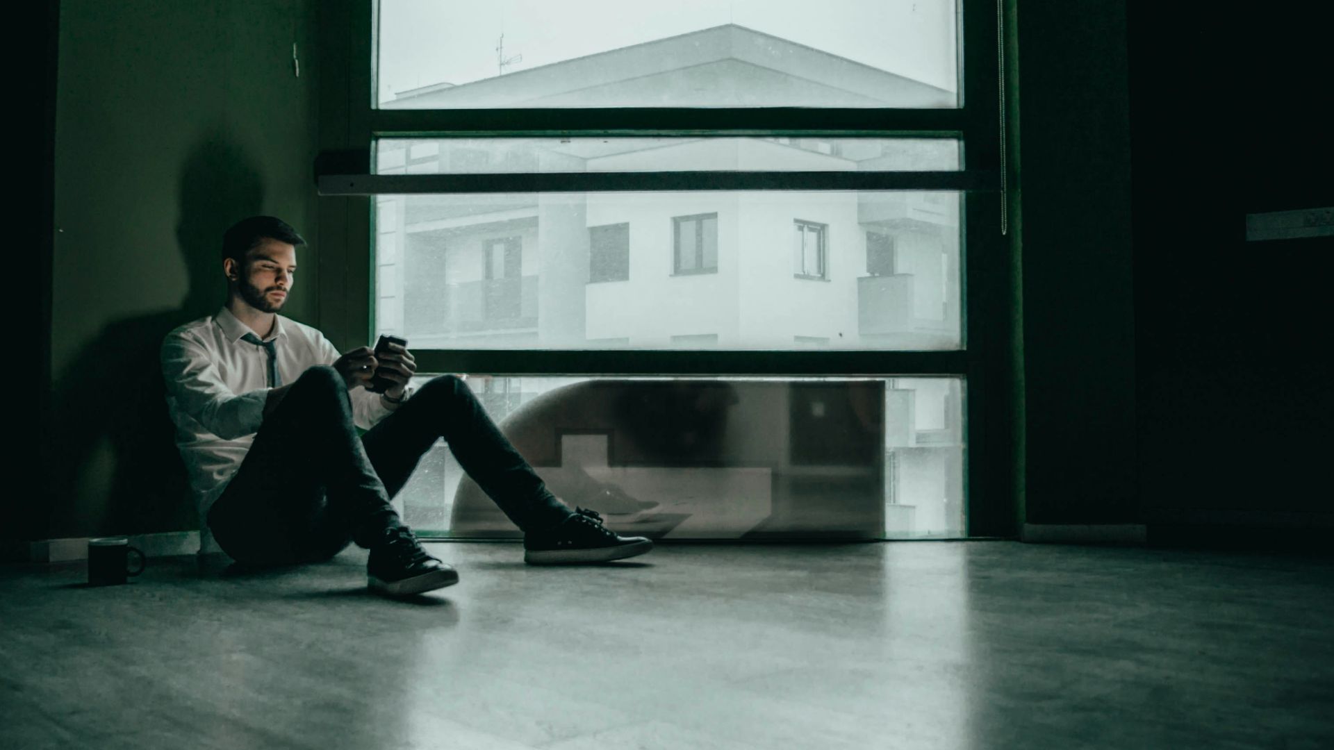 a man sitting on the floor looking at his cell phone