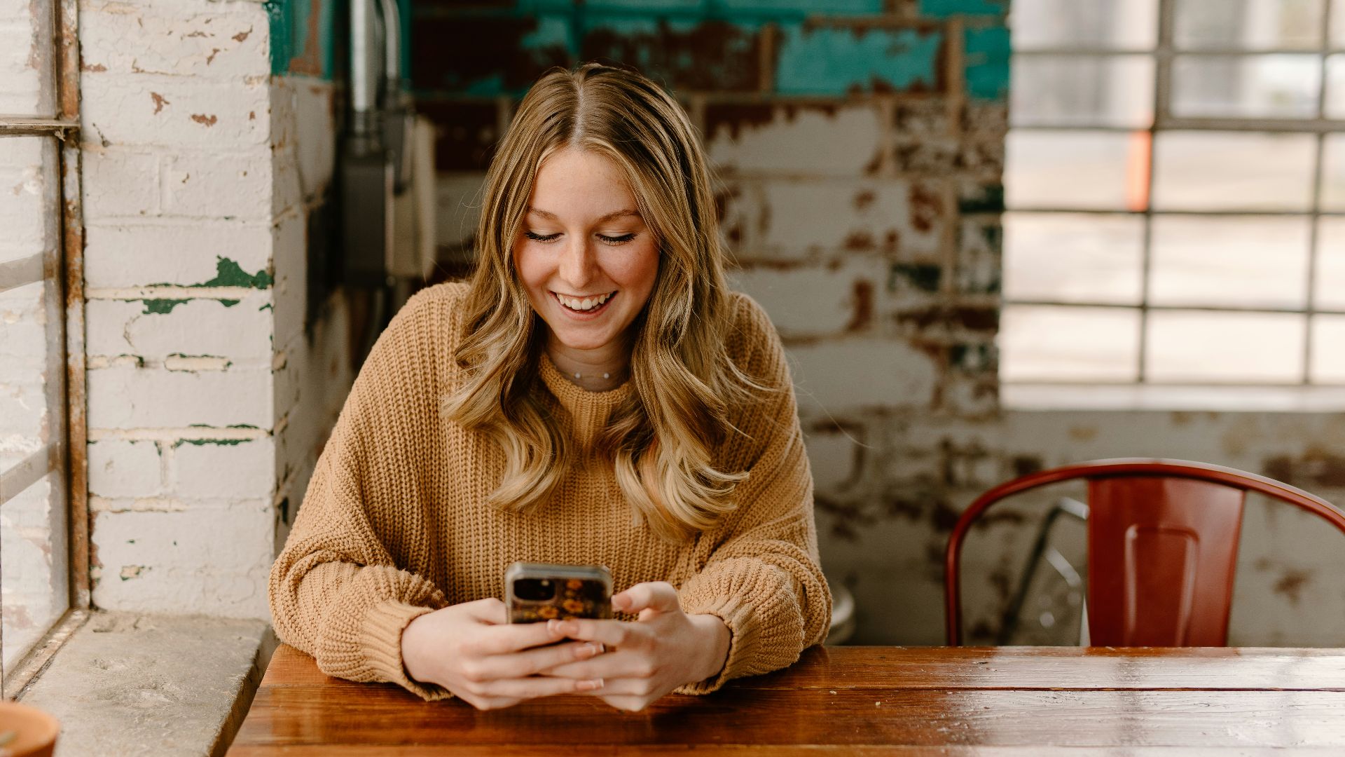 a woman sitting at a table looking at her cell phone