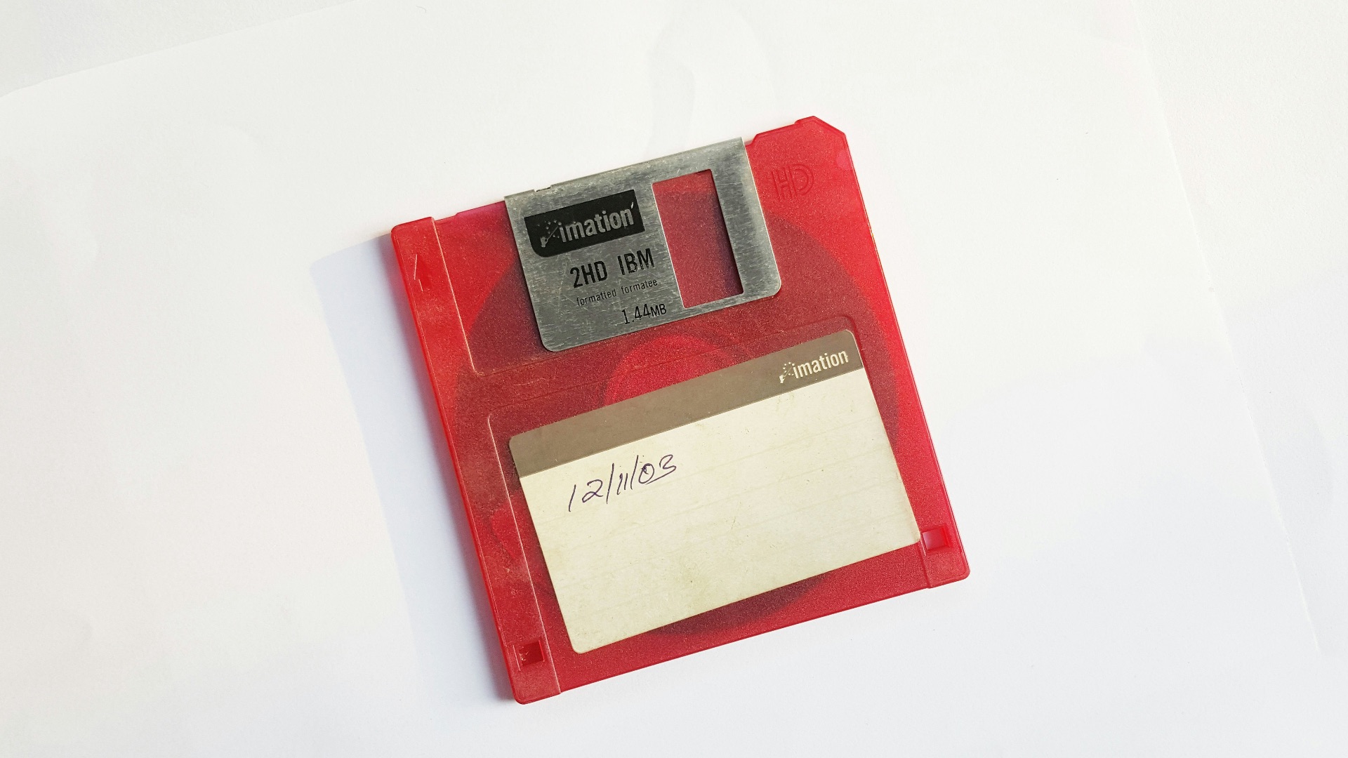 red and white floppy disk on white surface