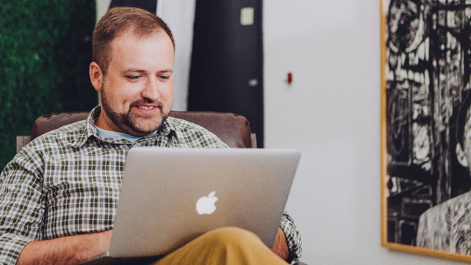 man smiling and using MacBook
