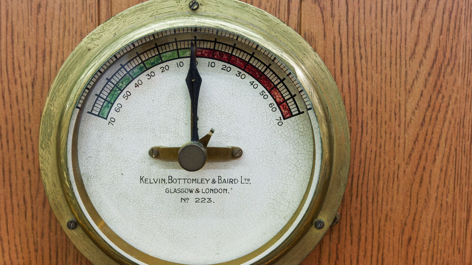 A close up of a thermometer on a wooden wall