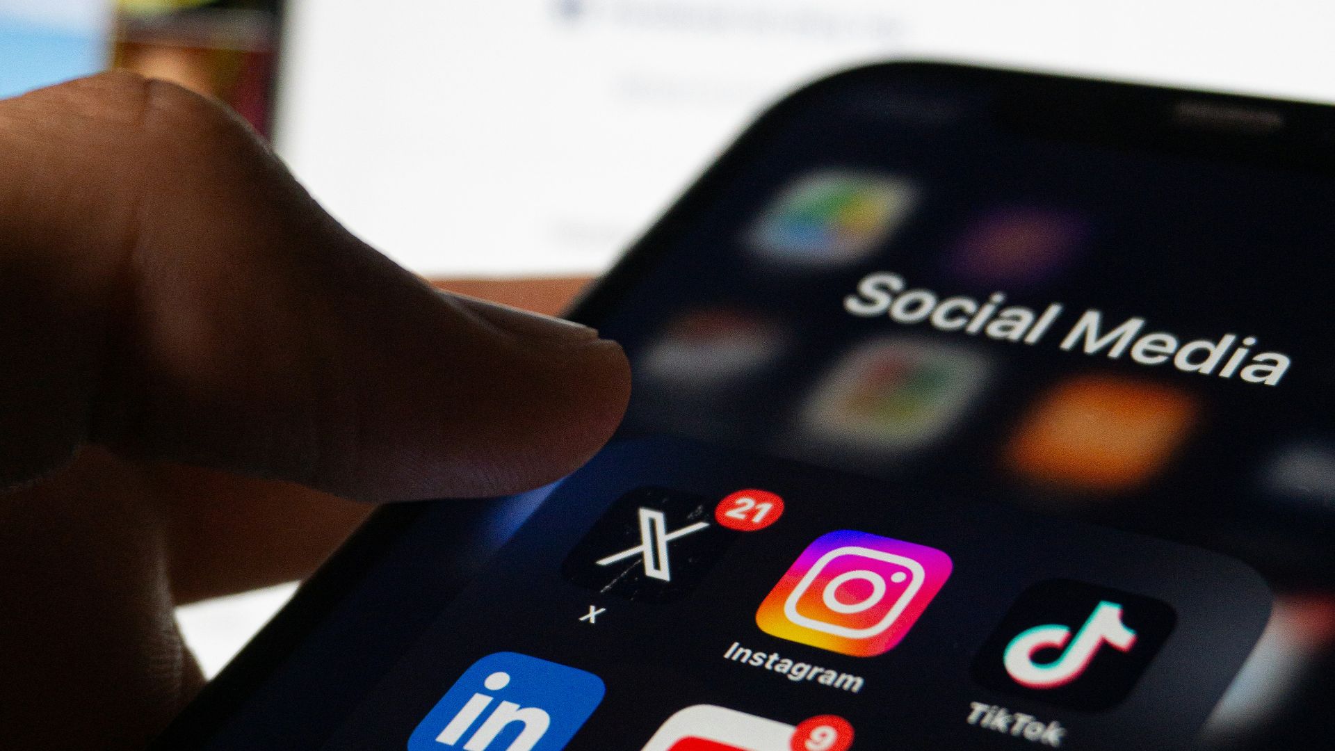 A person holding a smart phone with social media on the screen