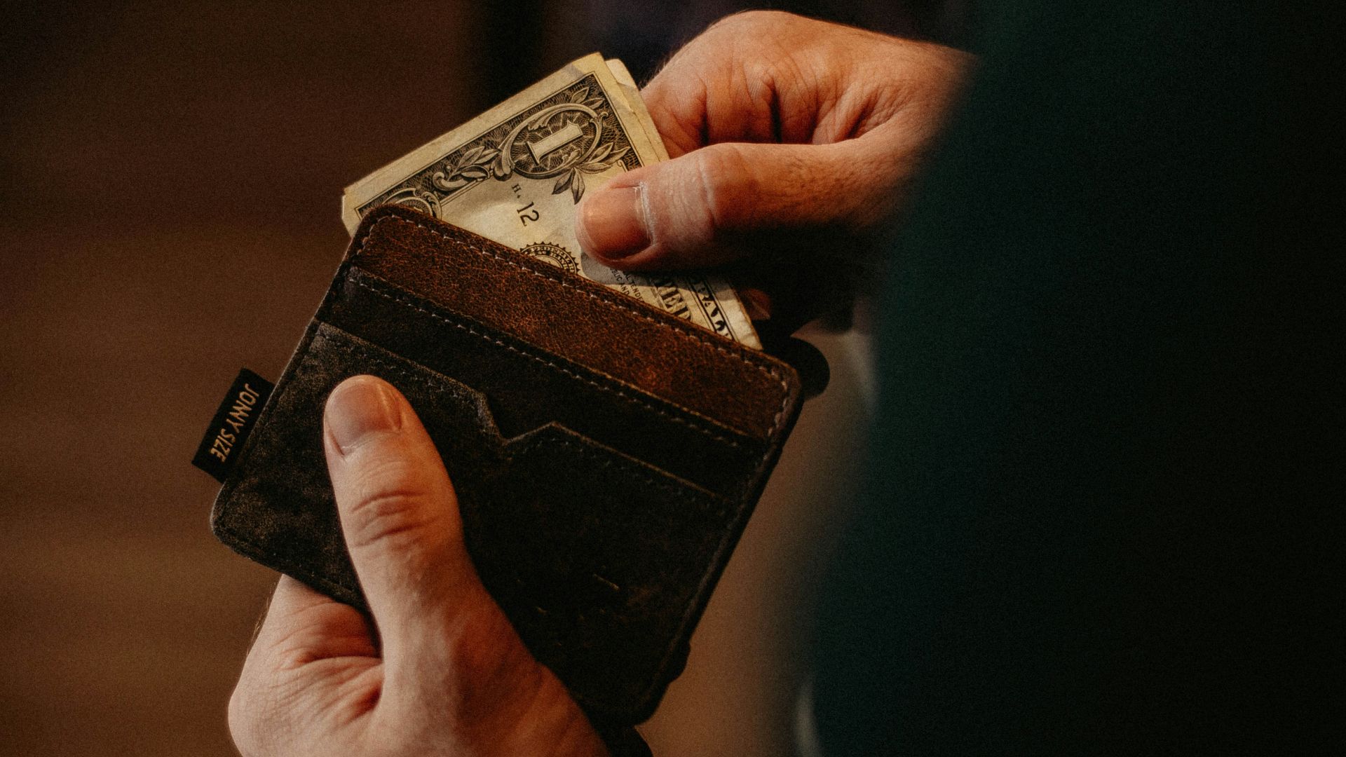 person getting 1 U.S. dollar banknote in wallet
