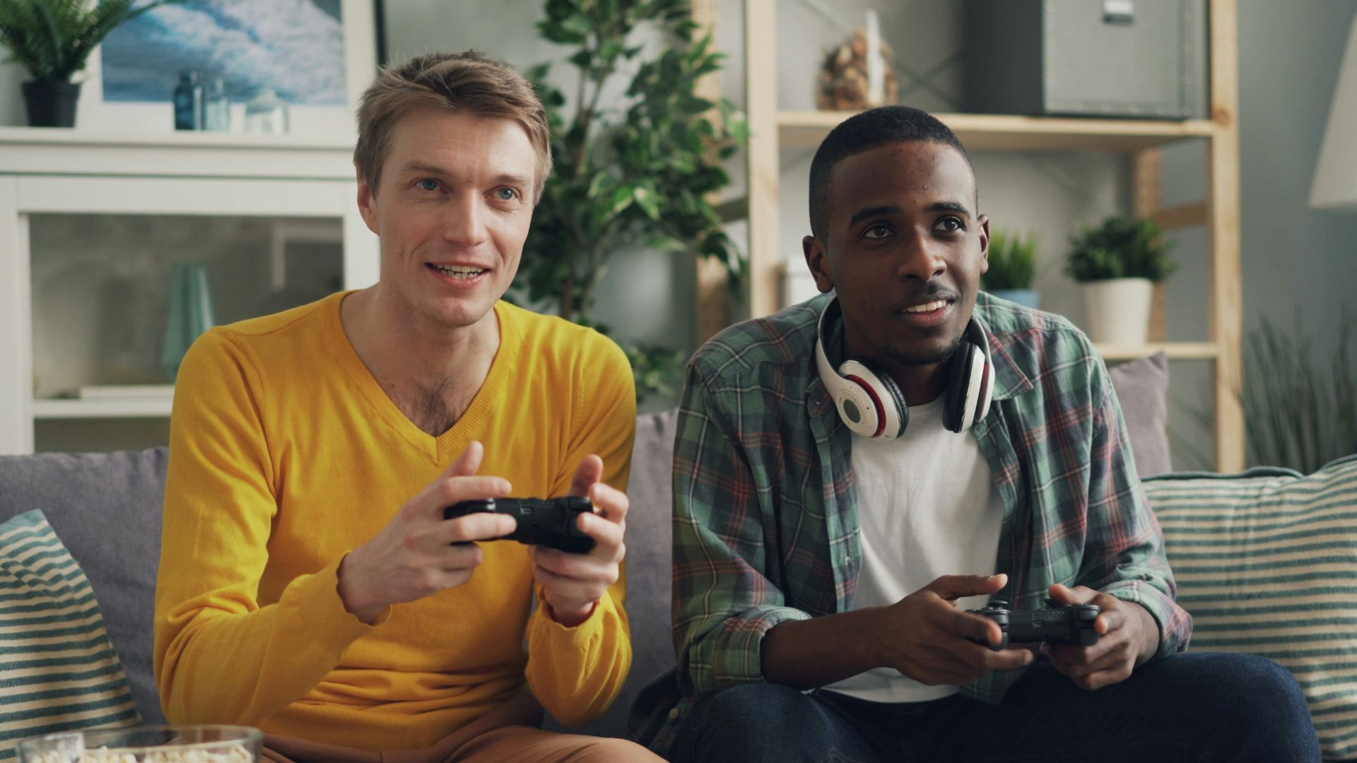 two men sitting on a couch playing video games