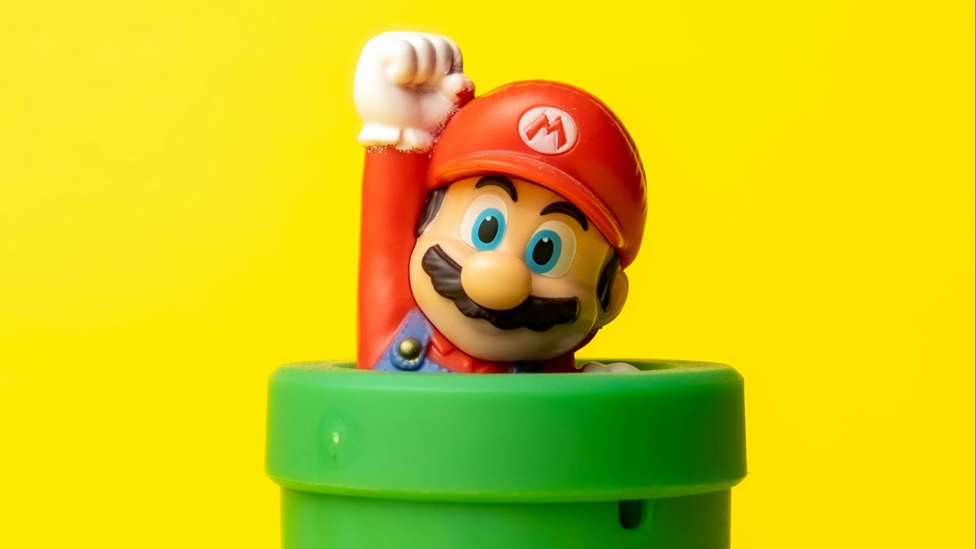 a toy mario in a green container on a yellow background