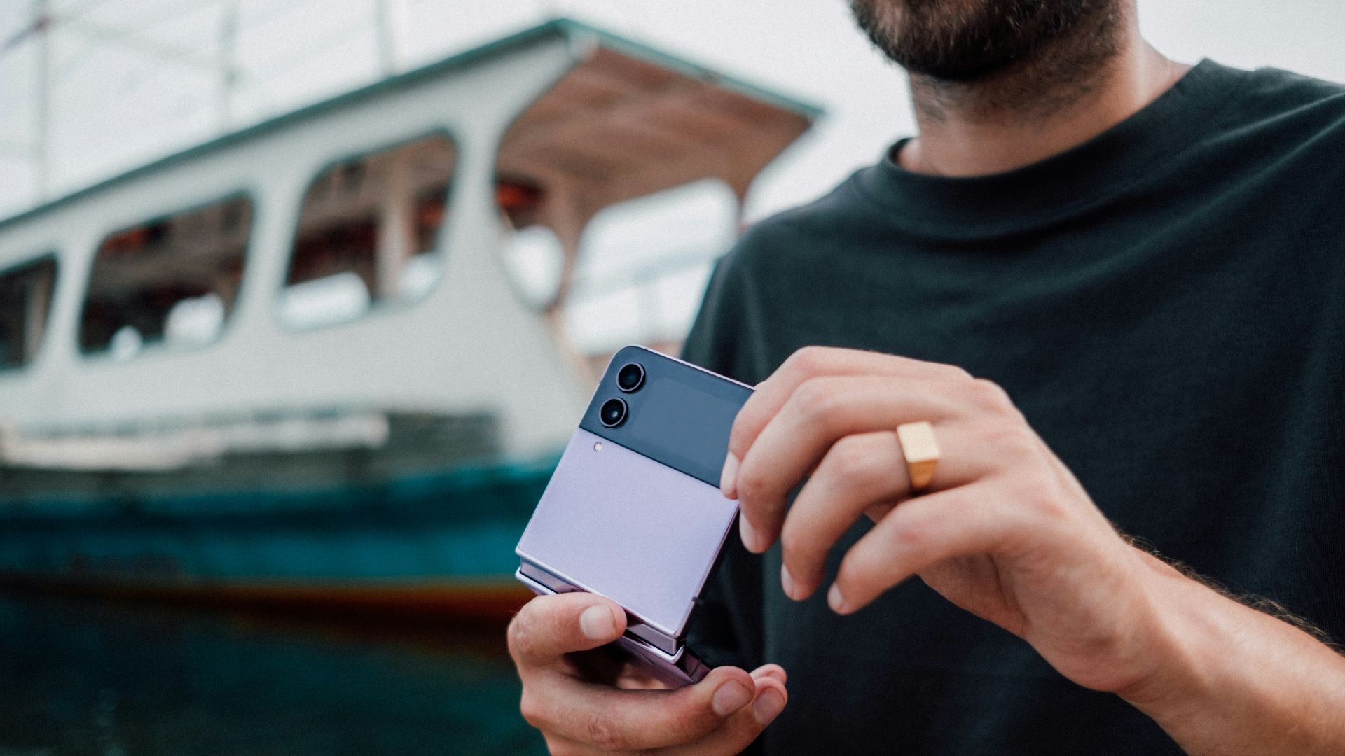 a man holding a cell phone in front of a boat
