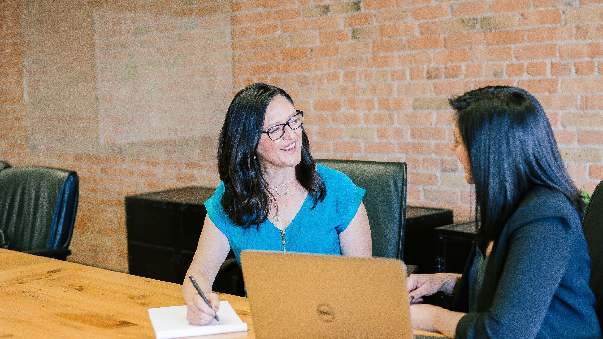 woman in teal t-shirt sitting beside woman in suit jacket
