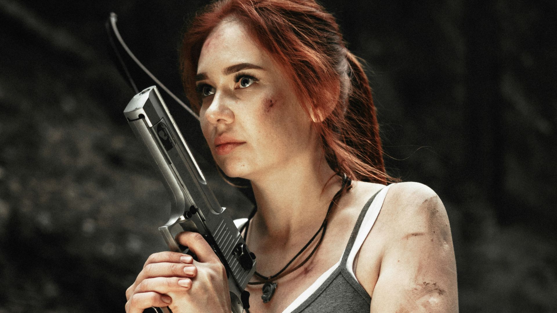 woman wearing gray spaghetti strap blouse holding gray rifle