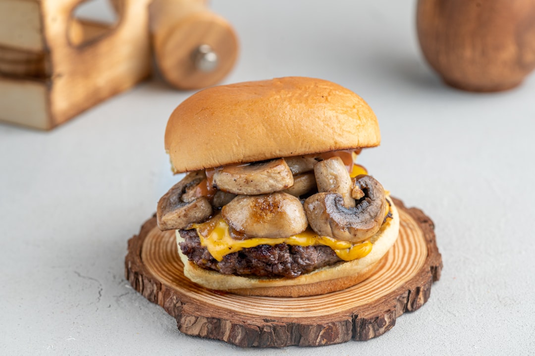 a cheeseburger with mushrooms on a wooden plate