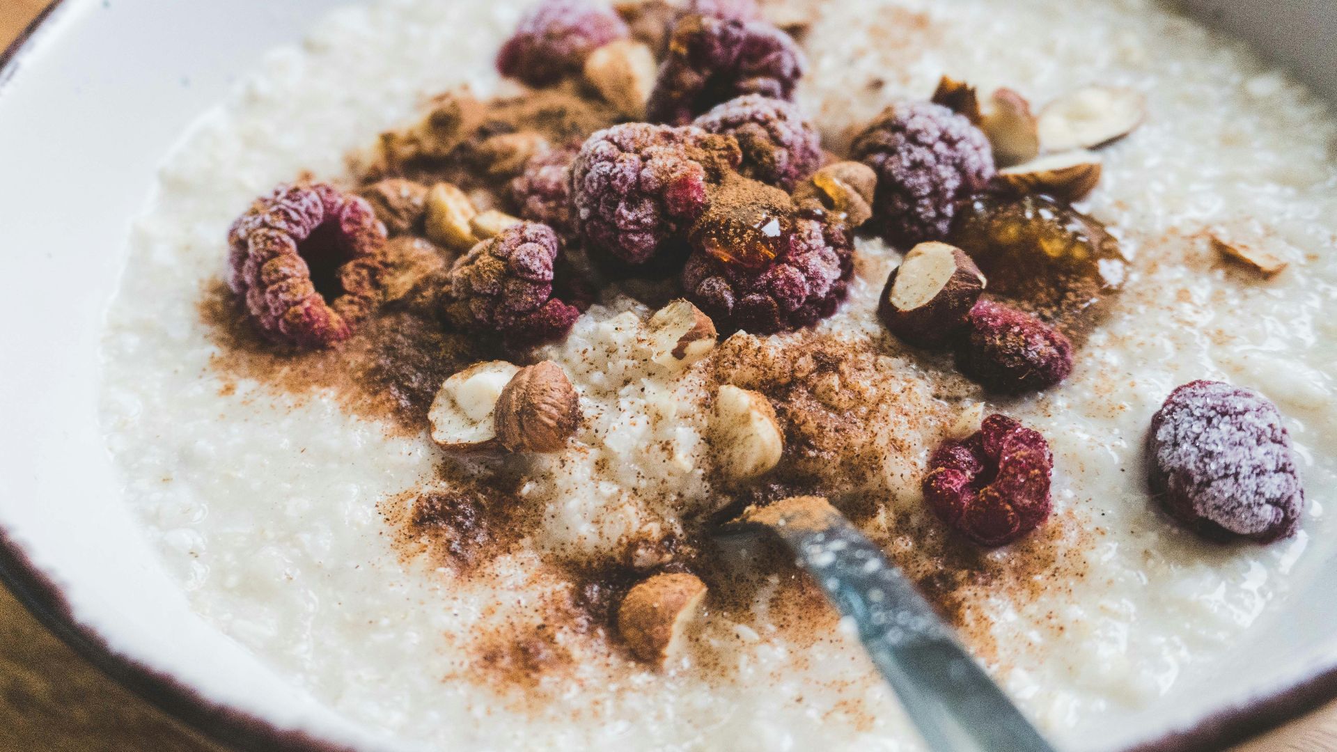 a bowl of oatmeal topped with nuts and raspberries