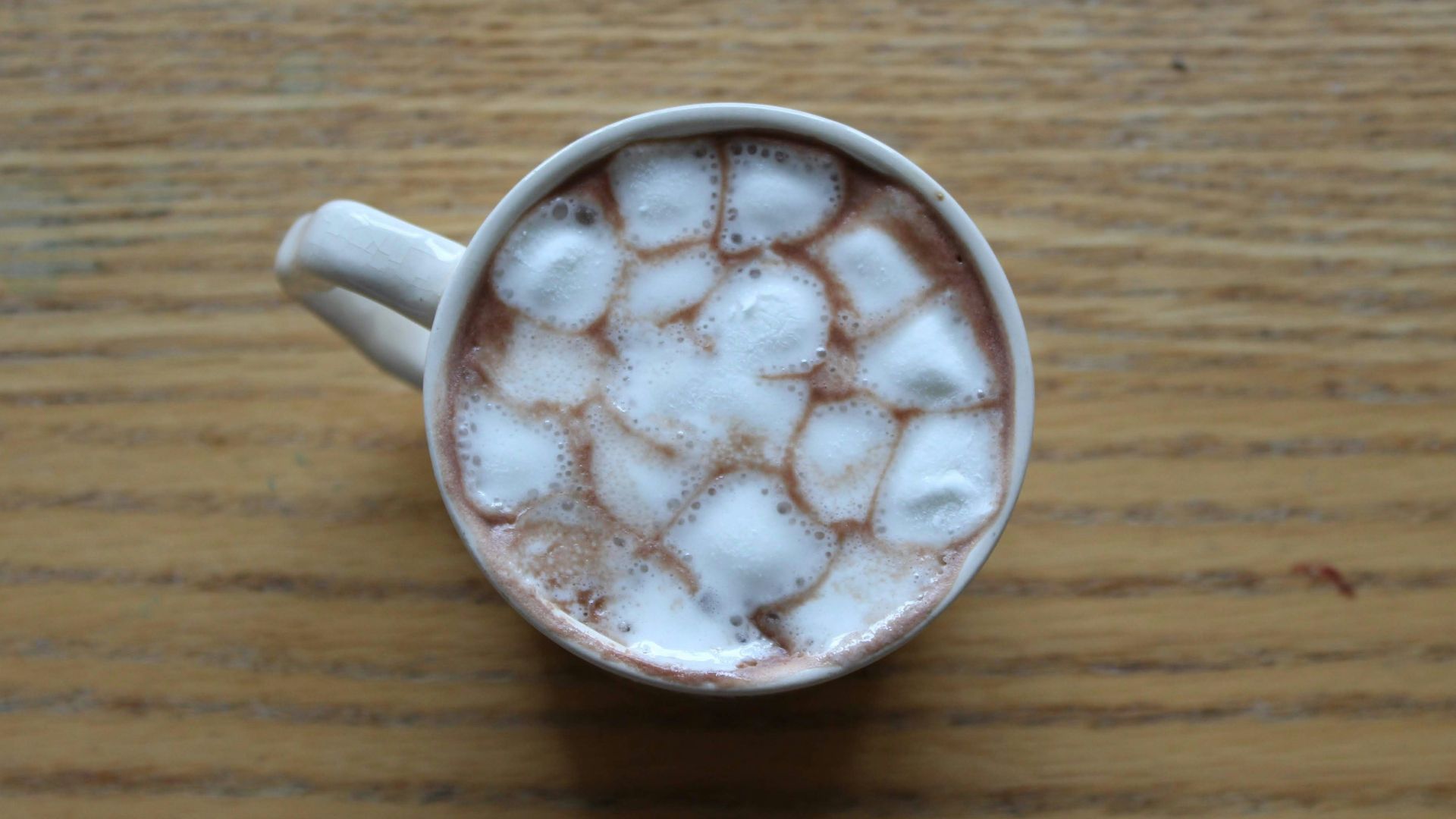 mug with beverage and marshmallows on wooden surface
