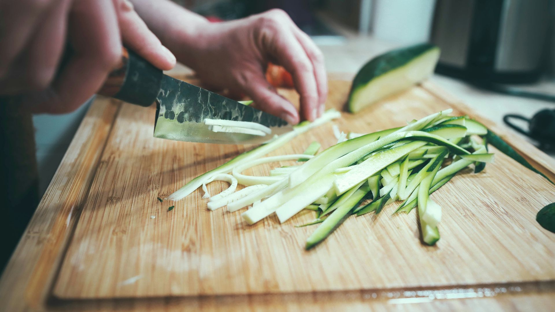 person slicing cucumber