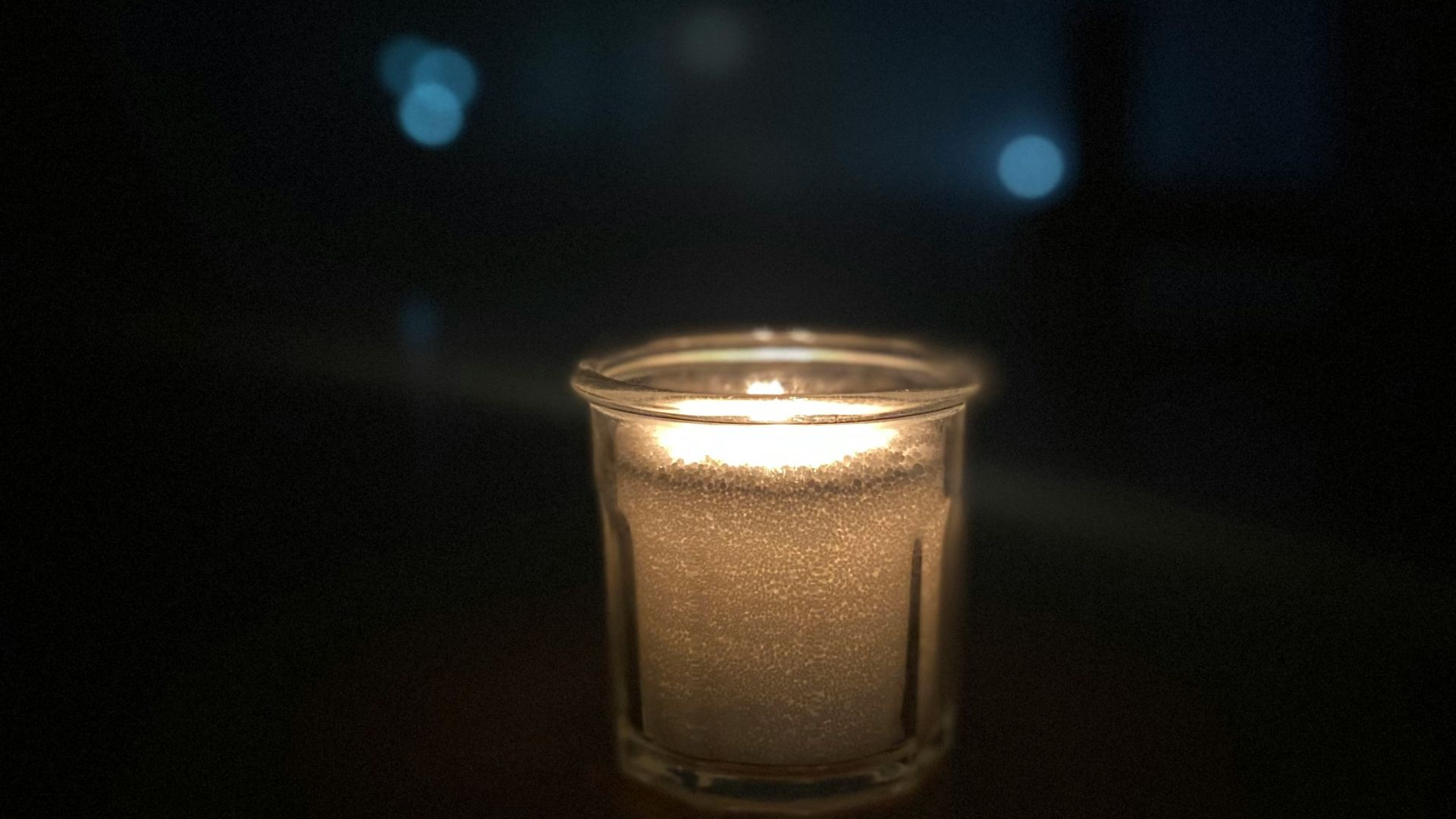 a lit candle sitting on a table in the dark