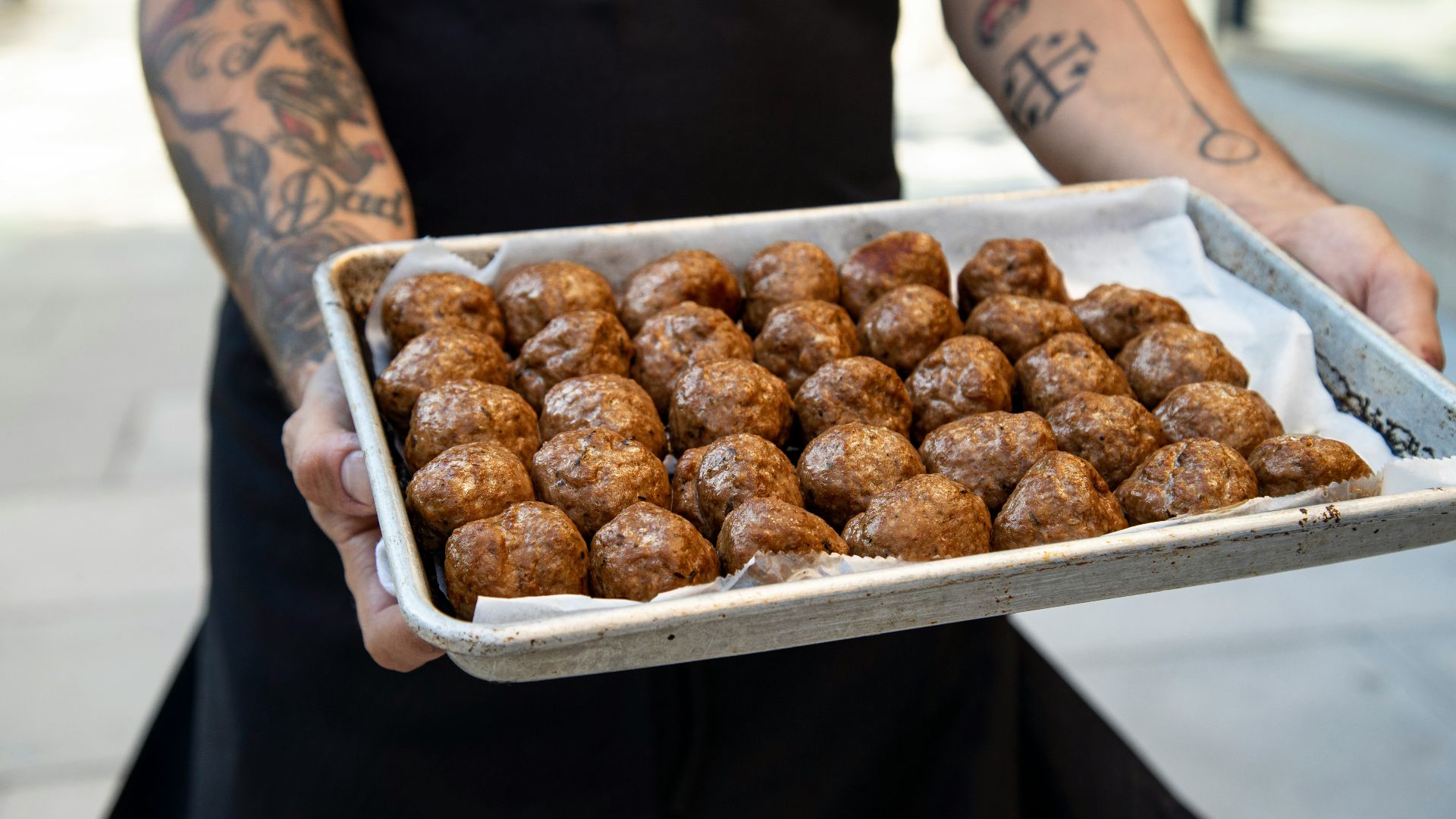 a person holding a tray of doughnuts on a sidewalk