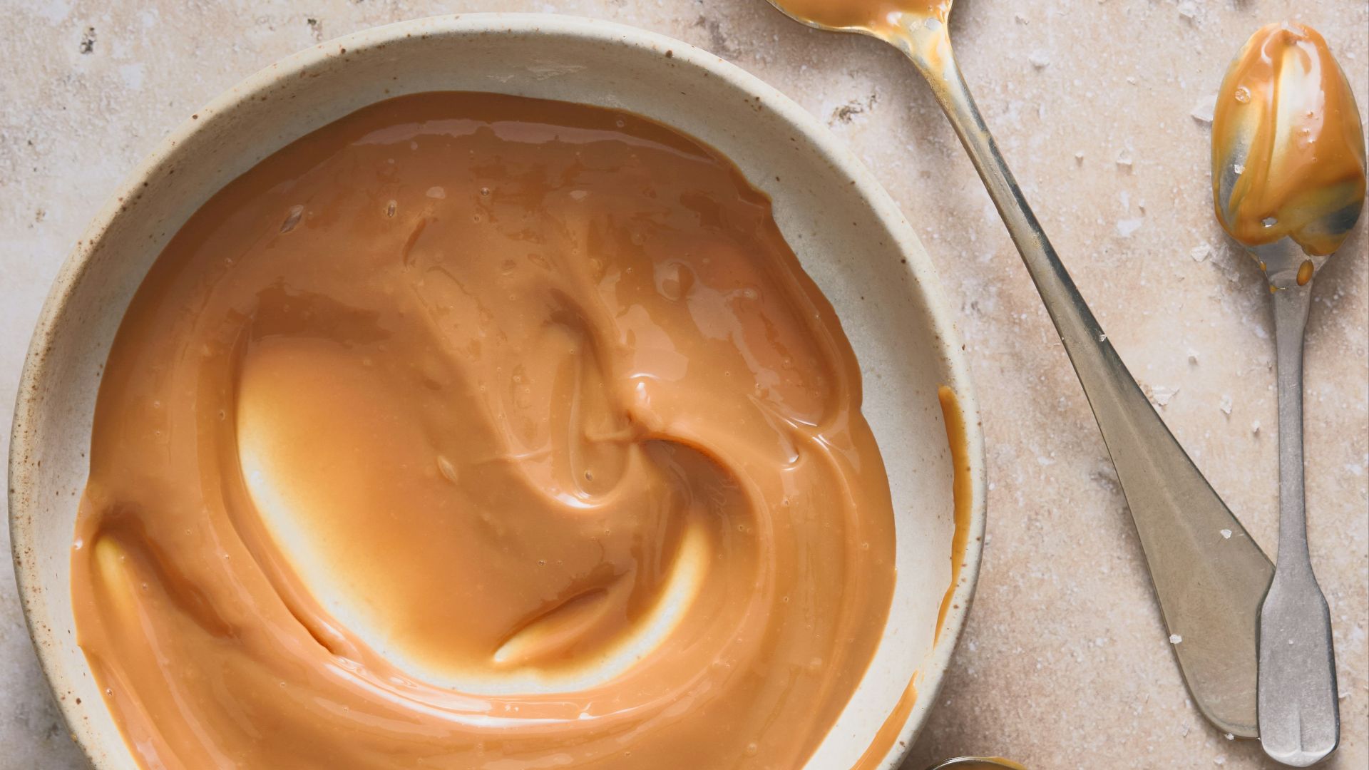 A bowl of peanut butter and spoons on a table