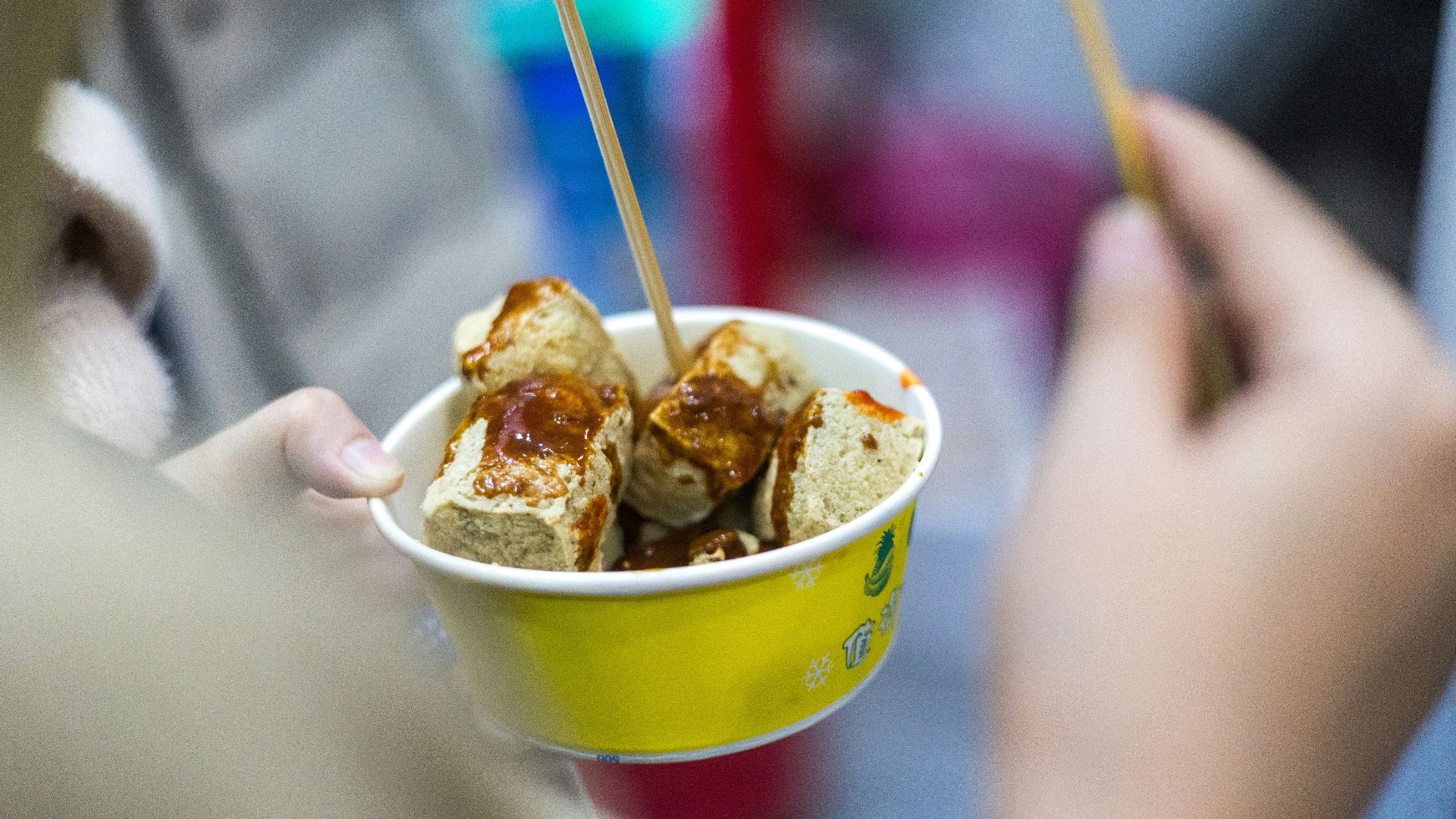 a person holding a yellow cup filled with food