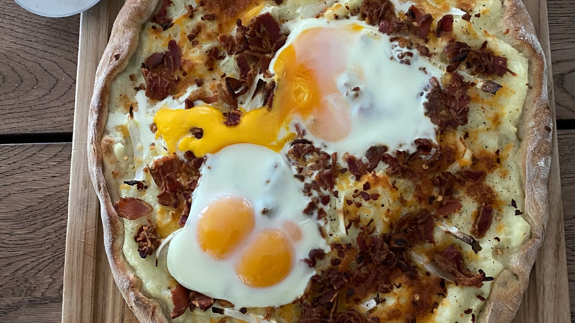 pizza with egg and cheese on brown wooden table