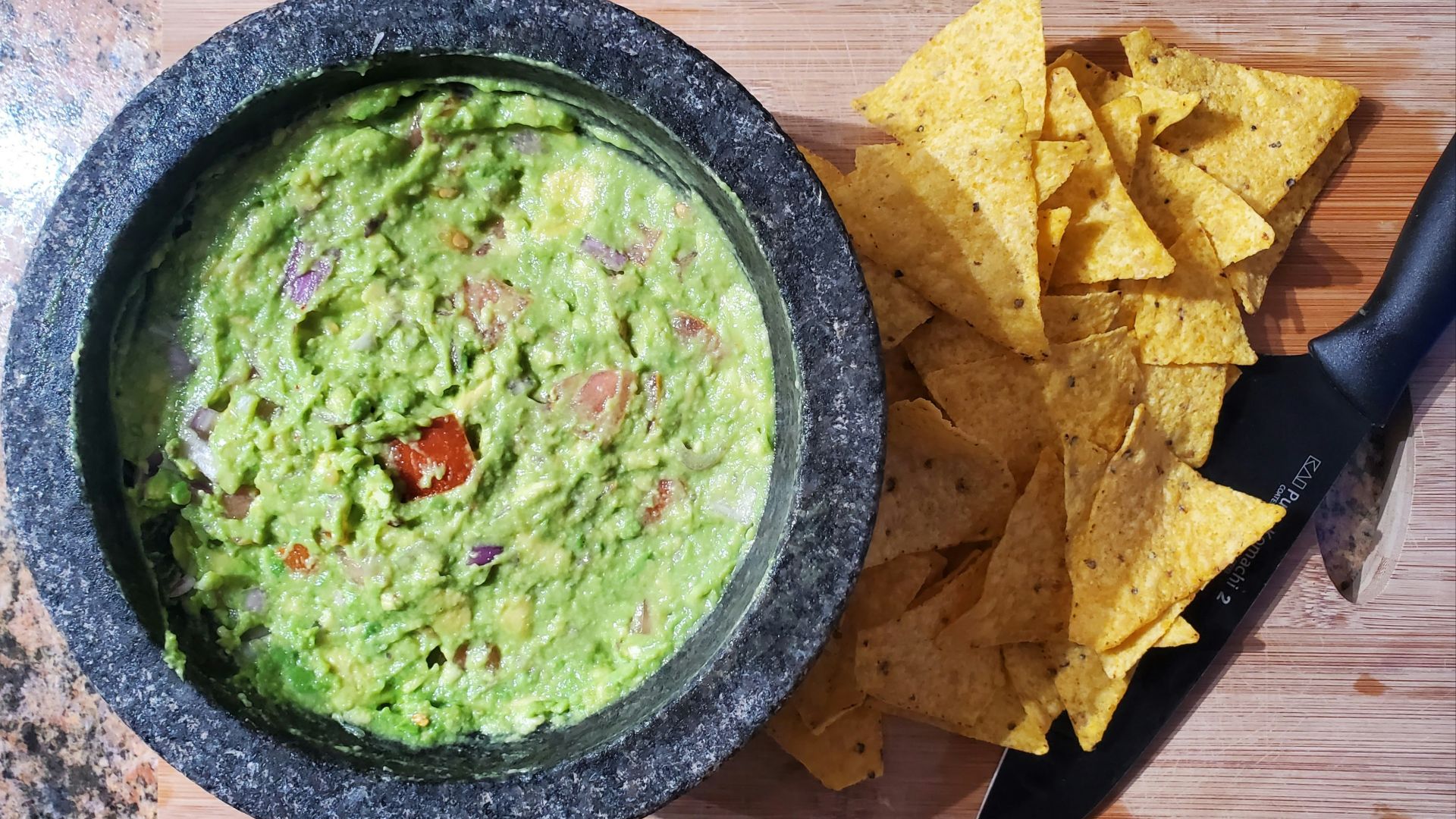 a bowl of guacamole next to a bowl of tortilla chips