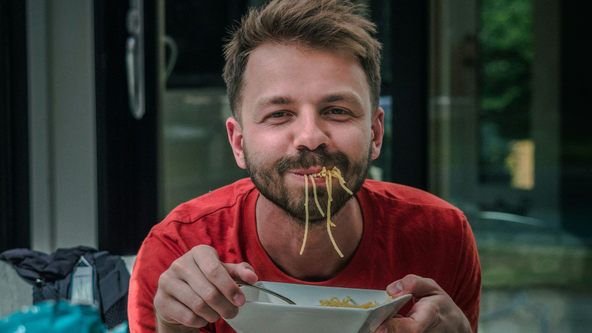 man in red crew neck t-shirt holding white and red labeled can
