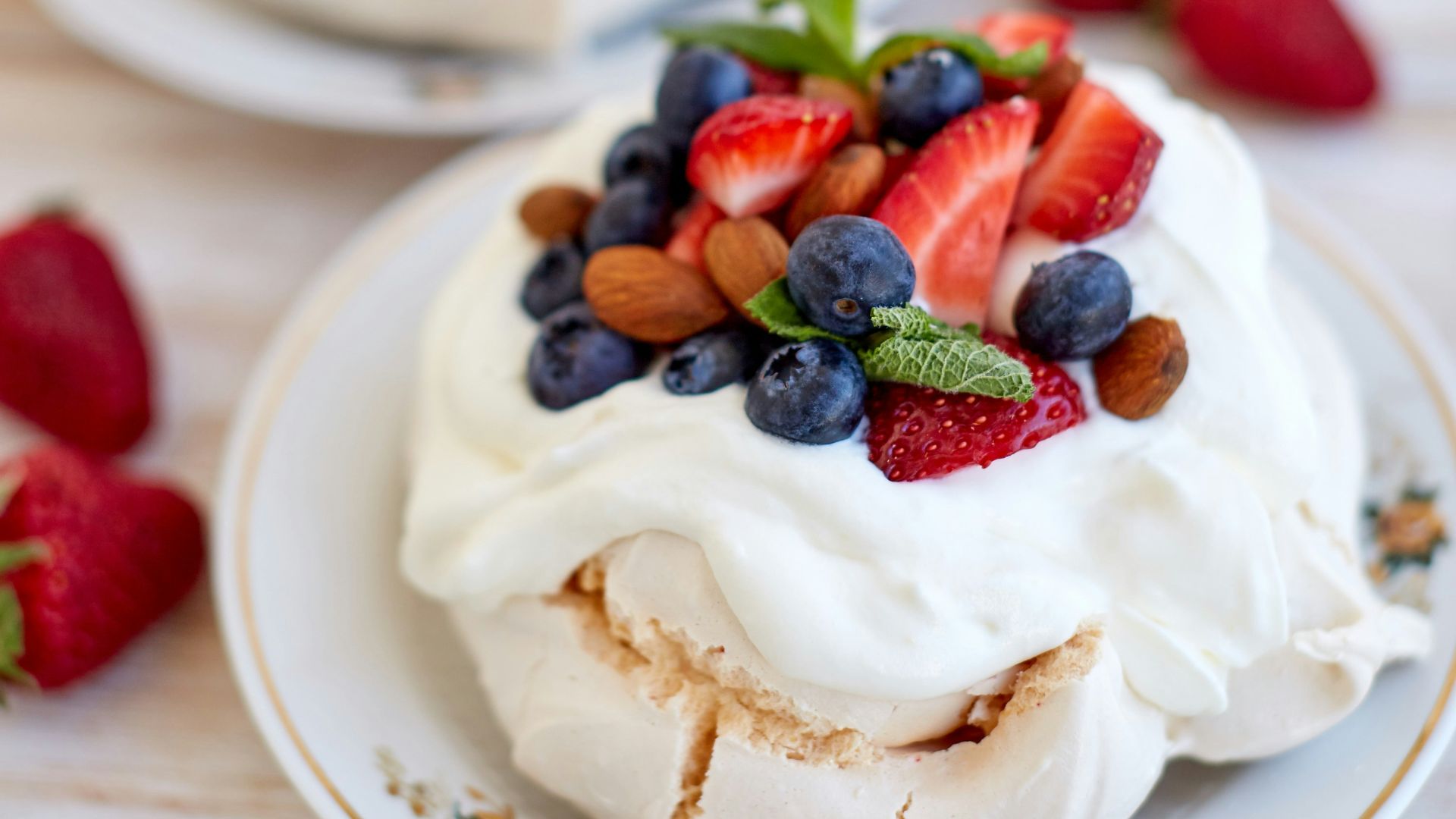 two desserts on a white plate with strawberries and blueberries