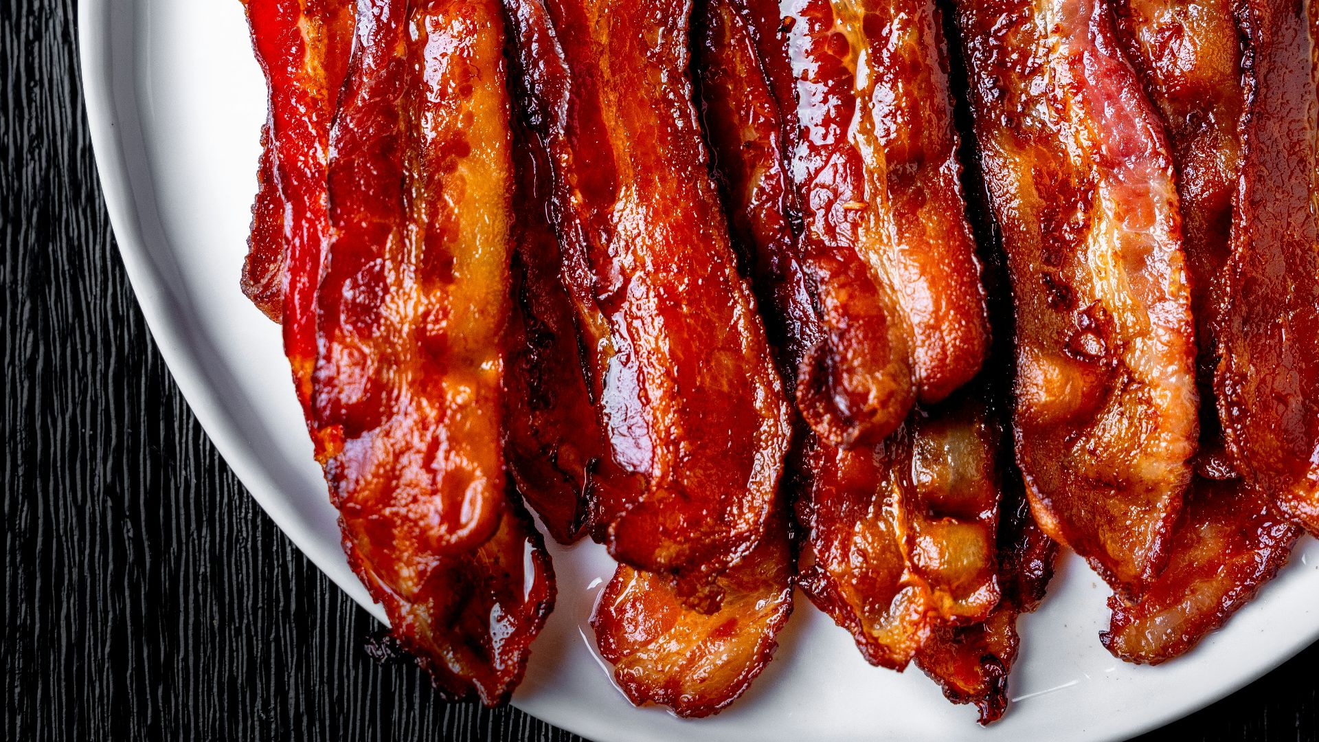 a white plate topped with bacon strips on top of a table