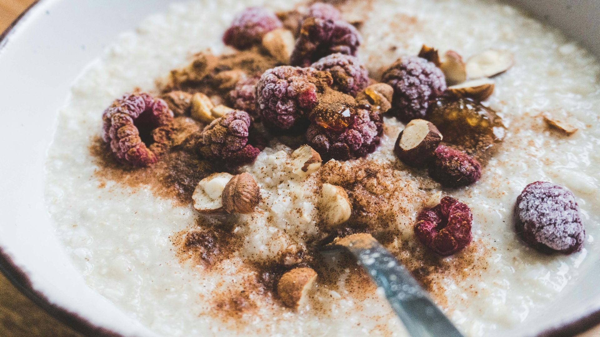 a bowl of oatmeal topped with nuts and raspberries