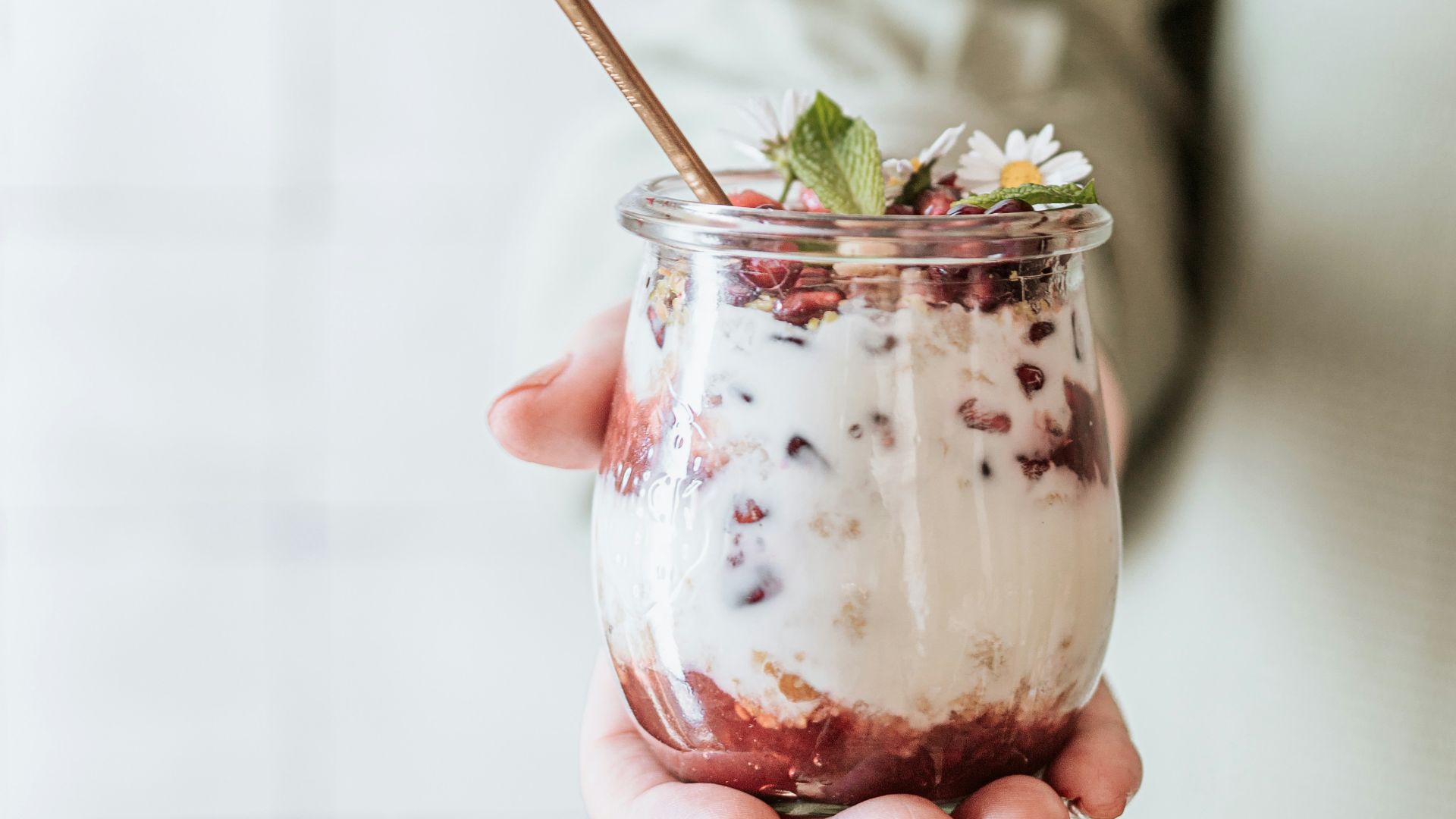 woman in white dress holding clear glass mug with green leaf