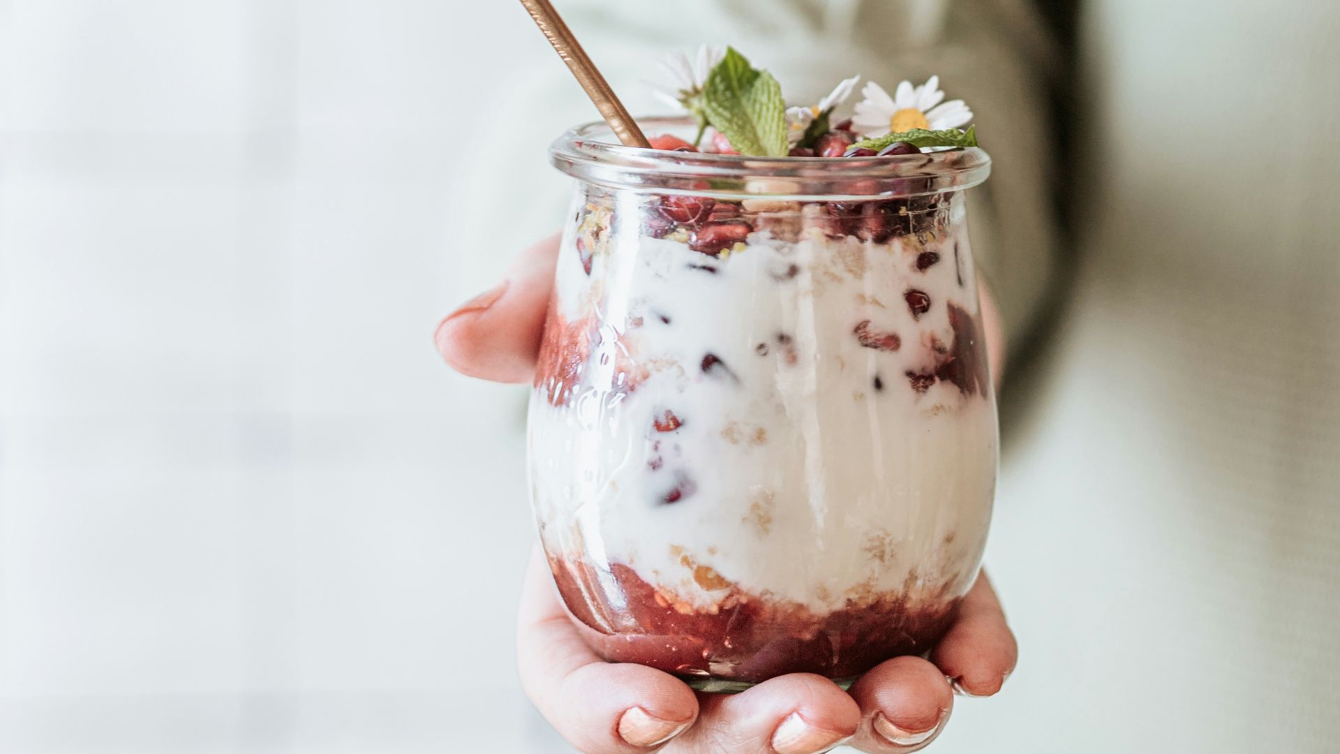 woman in white dress holding clear glass mug with green leaf