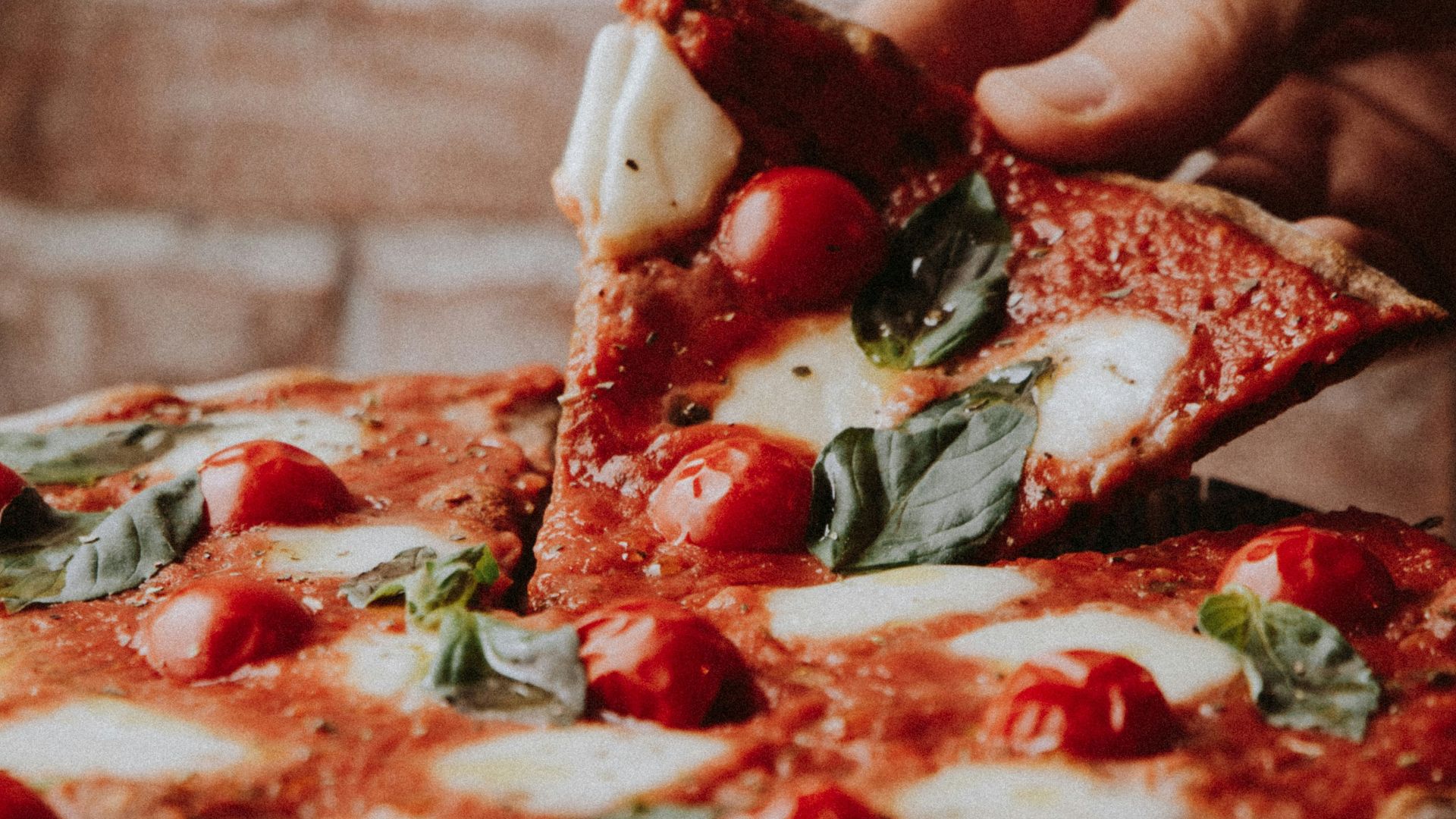 person holding sliced pizza with red sauce