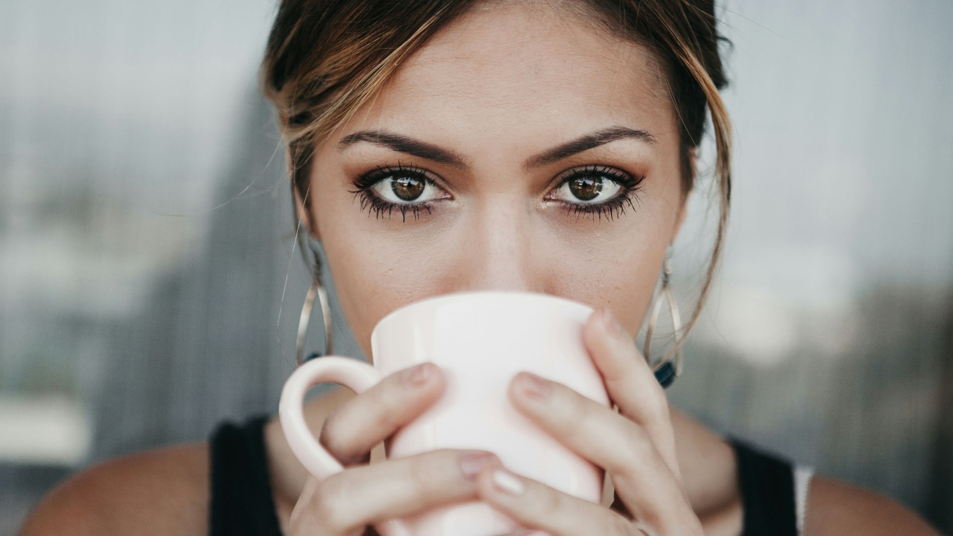 woman drinking from white coffee cup