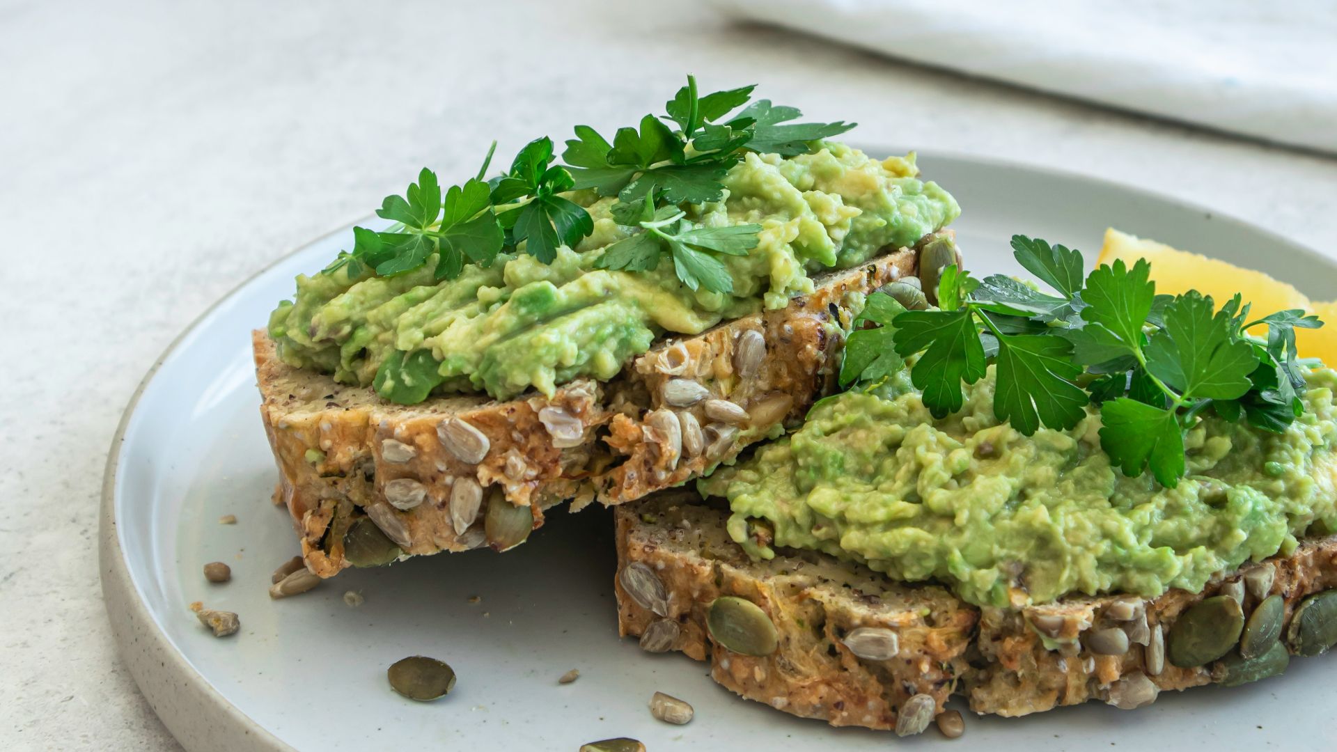 a white plate topped with a sandwich covered in guacamole