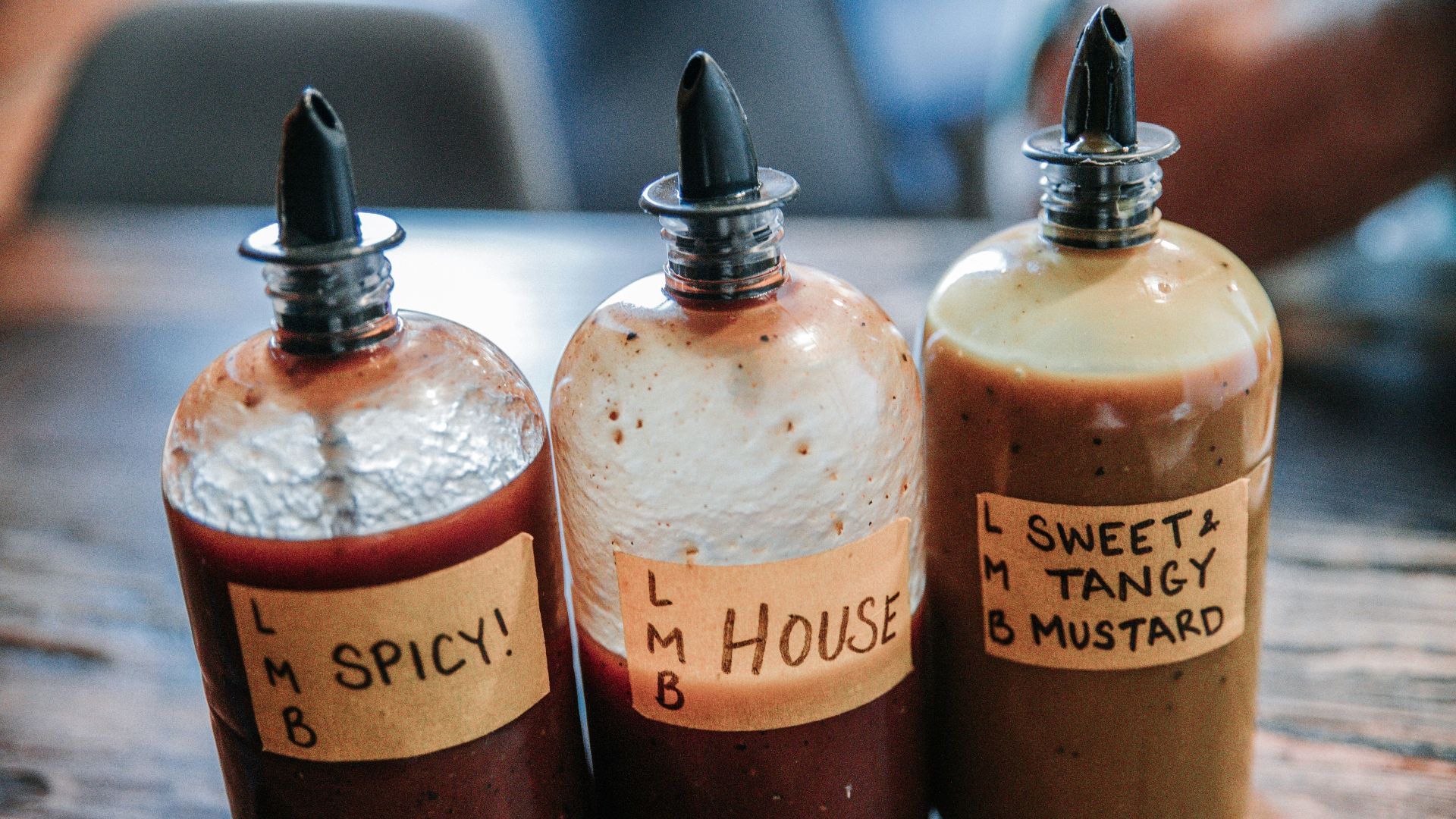 three filled condiment shakers on brown wooden surface