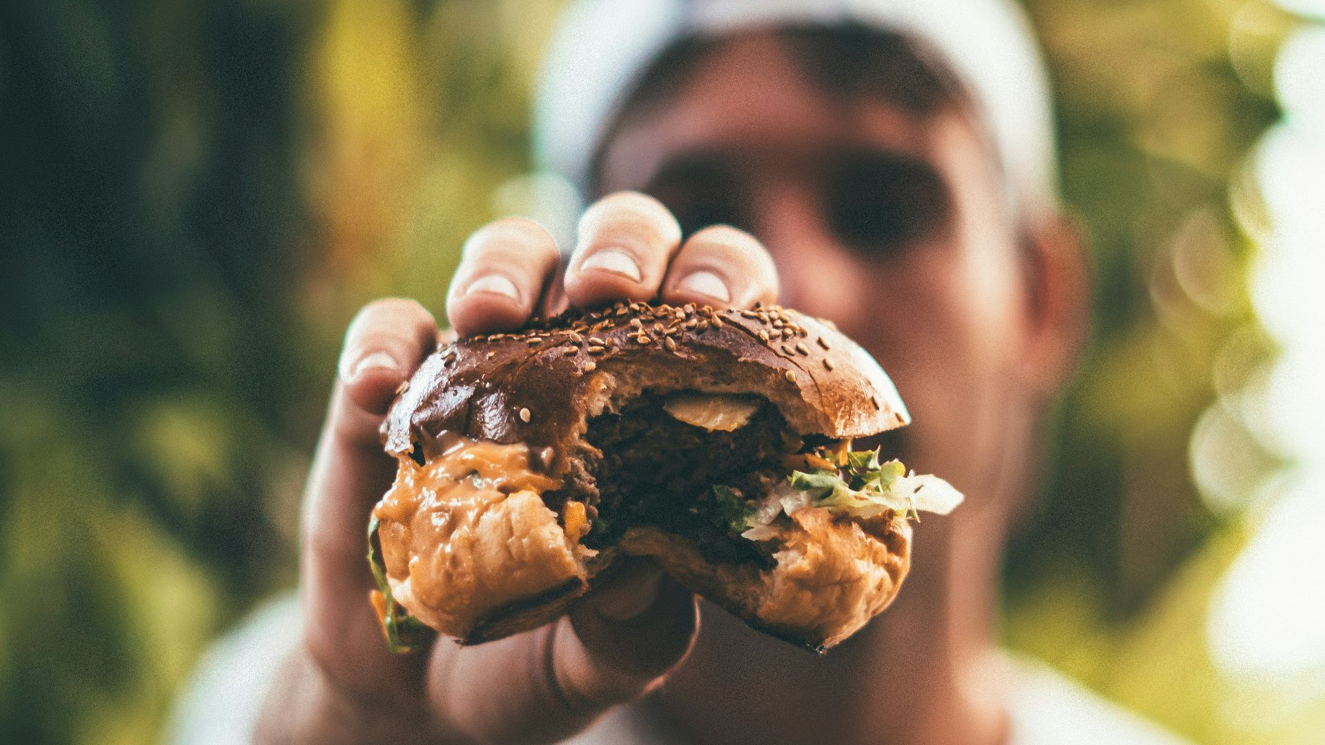 selective focus photography of man holding eaten burger