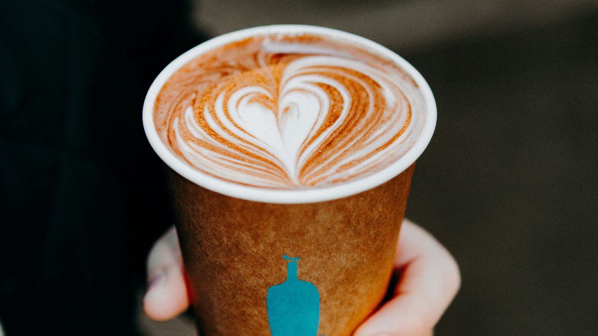person holding cup with brown liquid