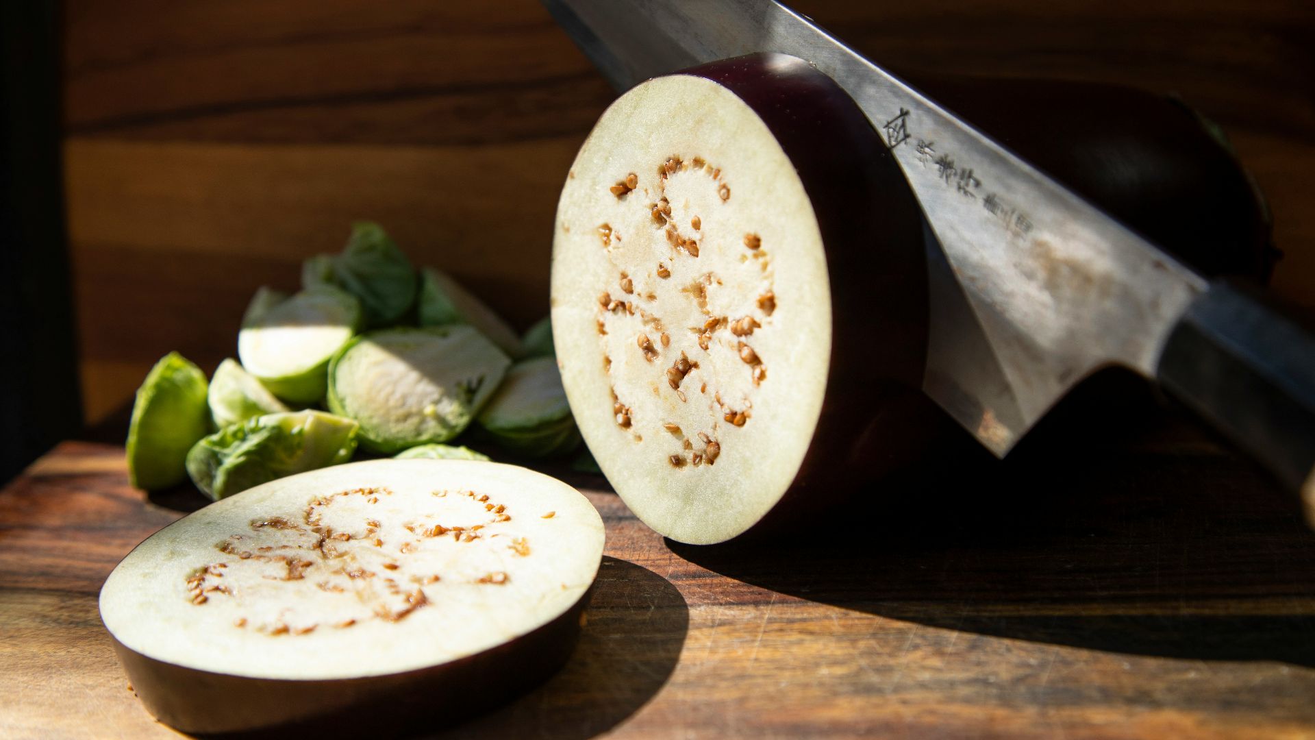 a sliced up eggplant next to a knife on a cutting board