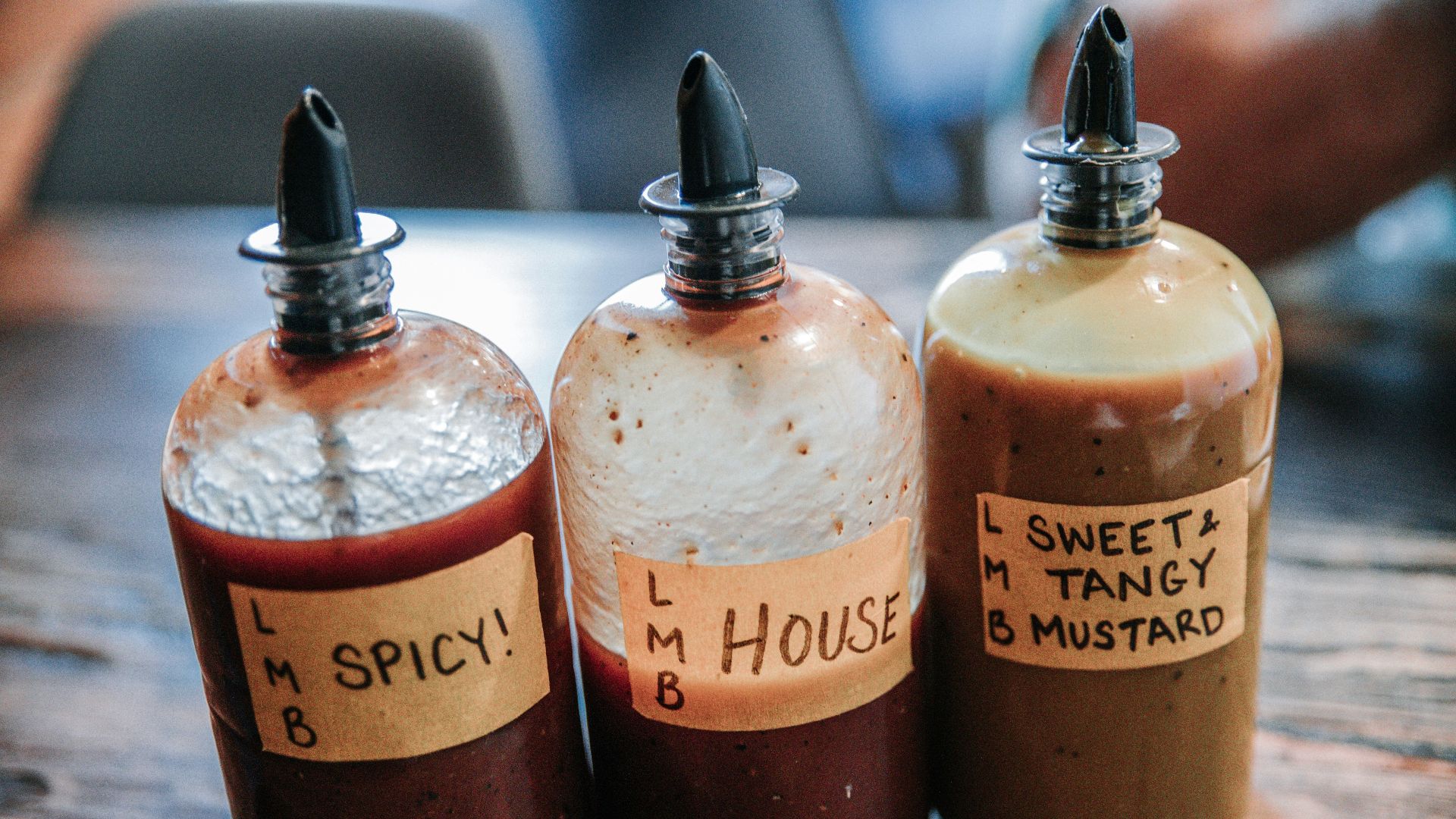 three filled condiment shakers on brown wooden surface