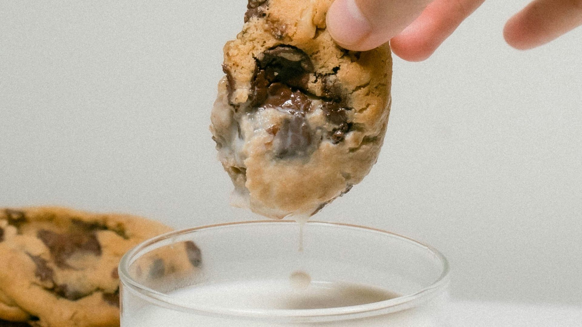 a person dipping a cookie into a glass of milk
